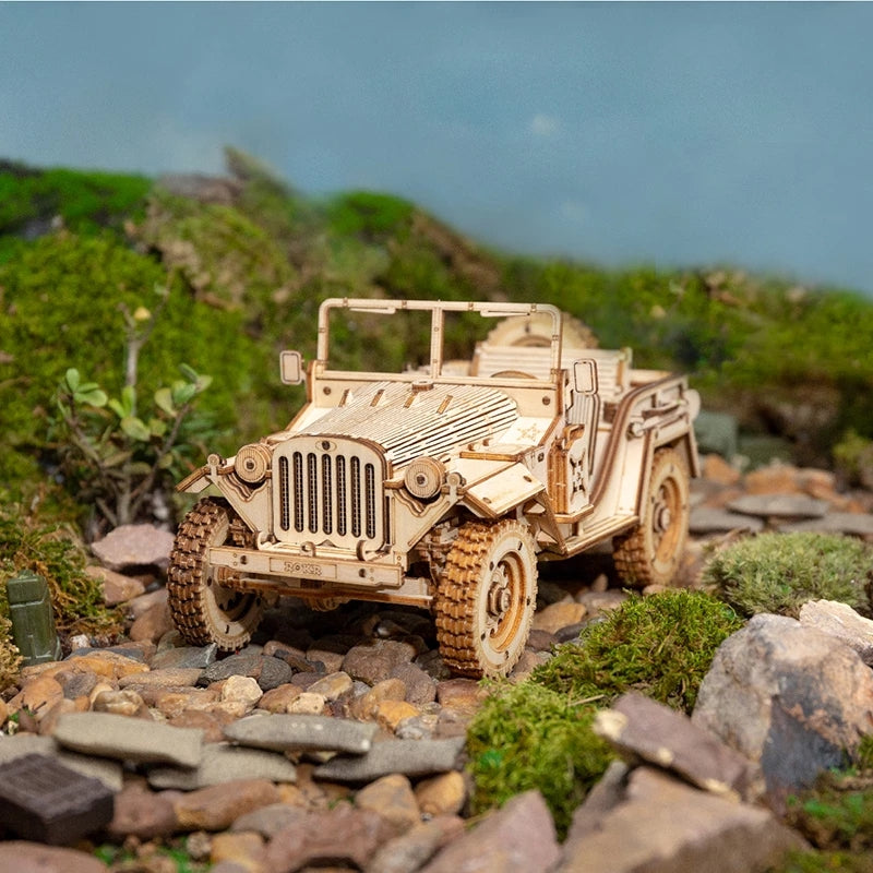 Model of a vintage military jeep on a rocky terrain with greenery.