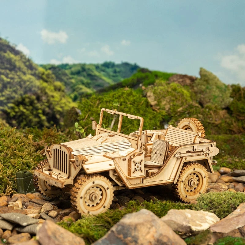 Wooden model of a jeep on a rocky landscape with green hills in the background