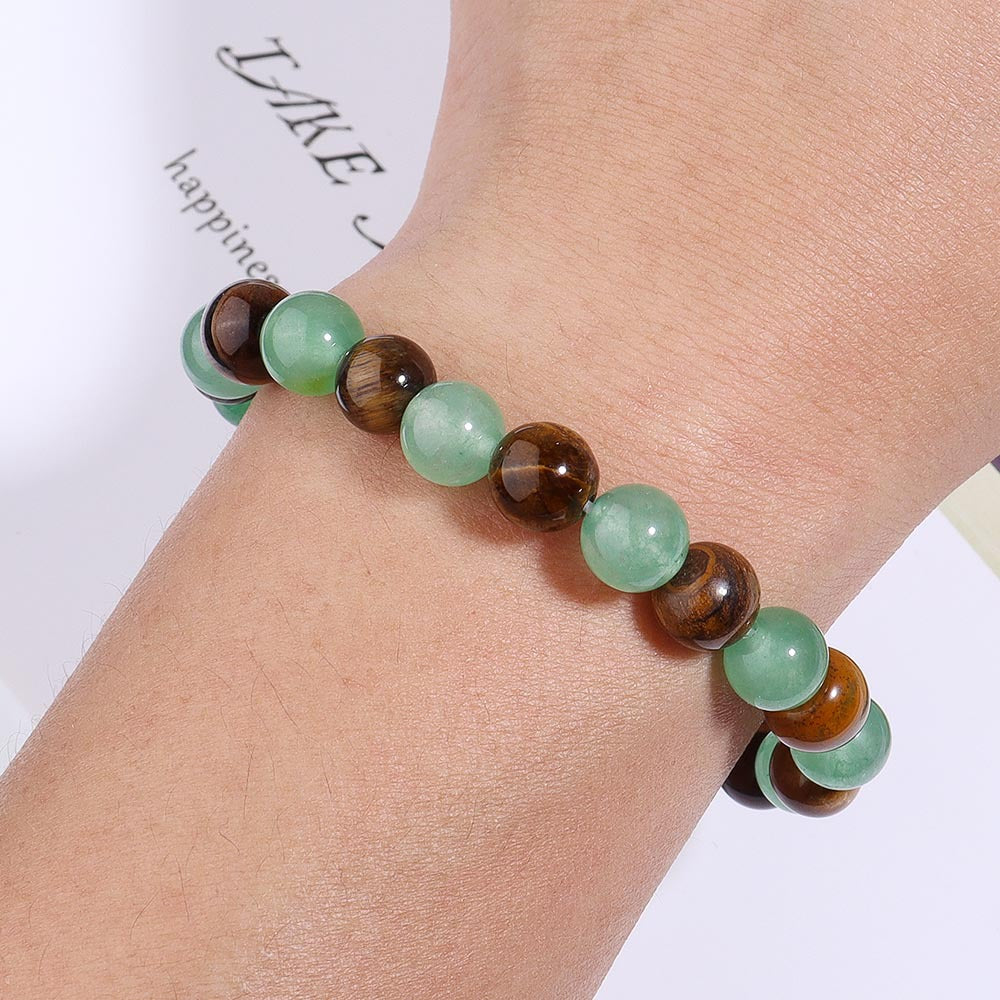 Beaded bracelet with green and brown beads on a wrist against a white background