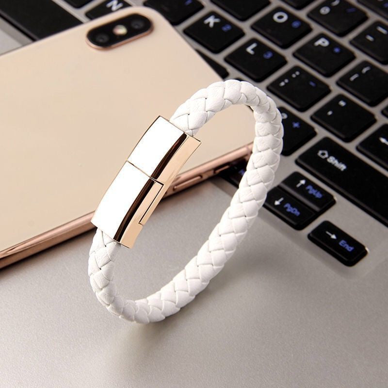 White braided bracelet with gold clasp on a laptop keyboard