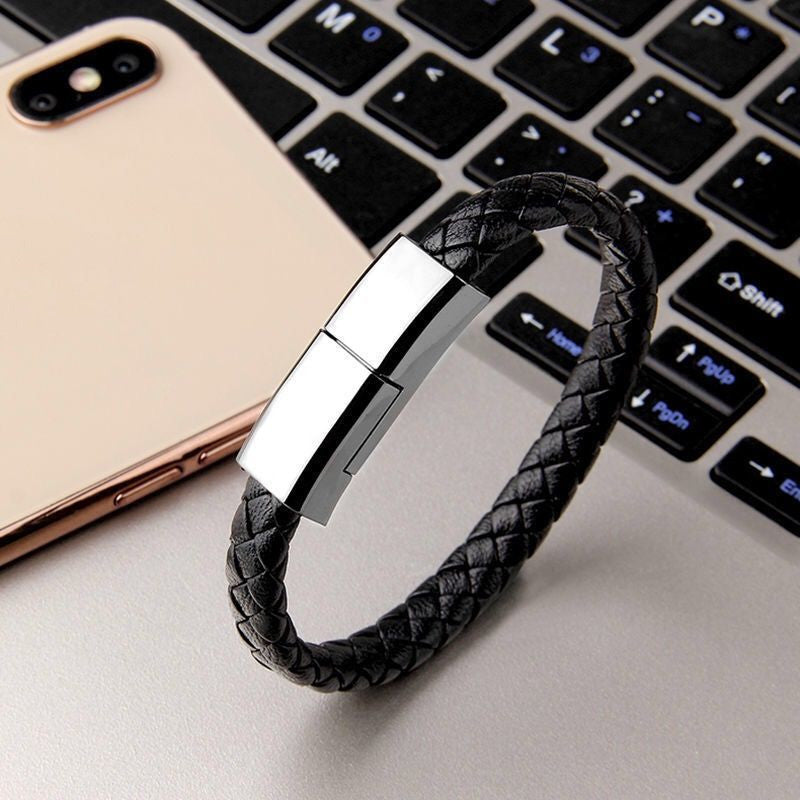 Black braided leather bracelet with silver clasp on a laptop keyboard