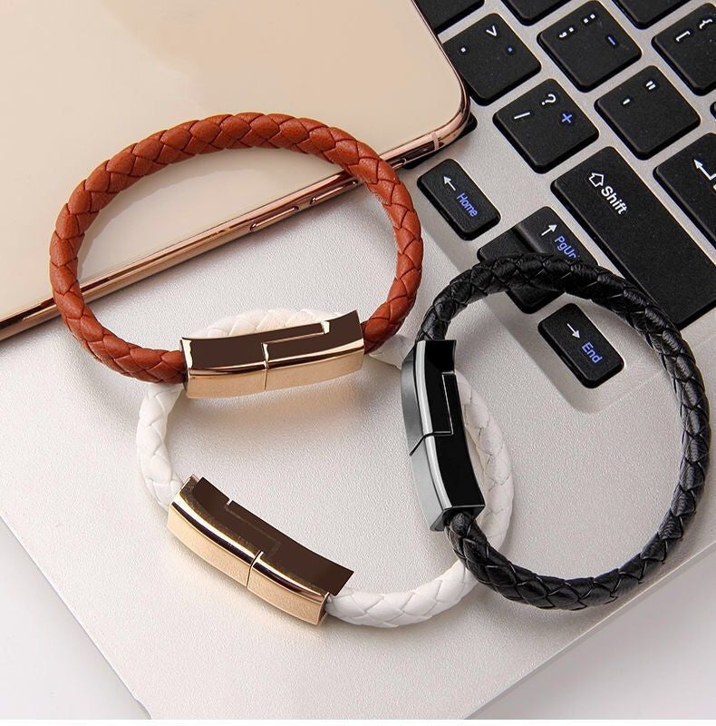 Three braided bracelets in brown, white, and black on a laptop keyboard.