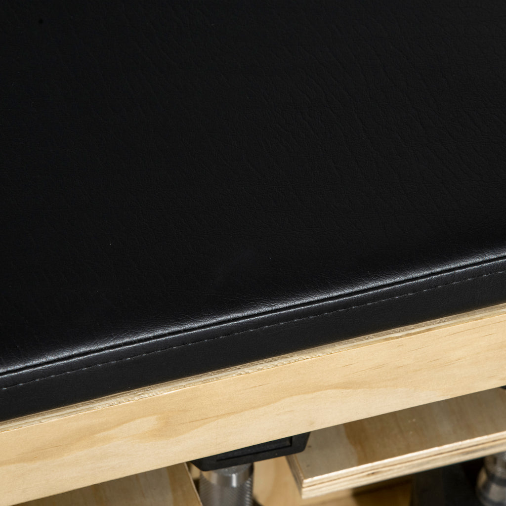 Close-up of a black leather seat and wooden frame on a vehicle interior.