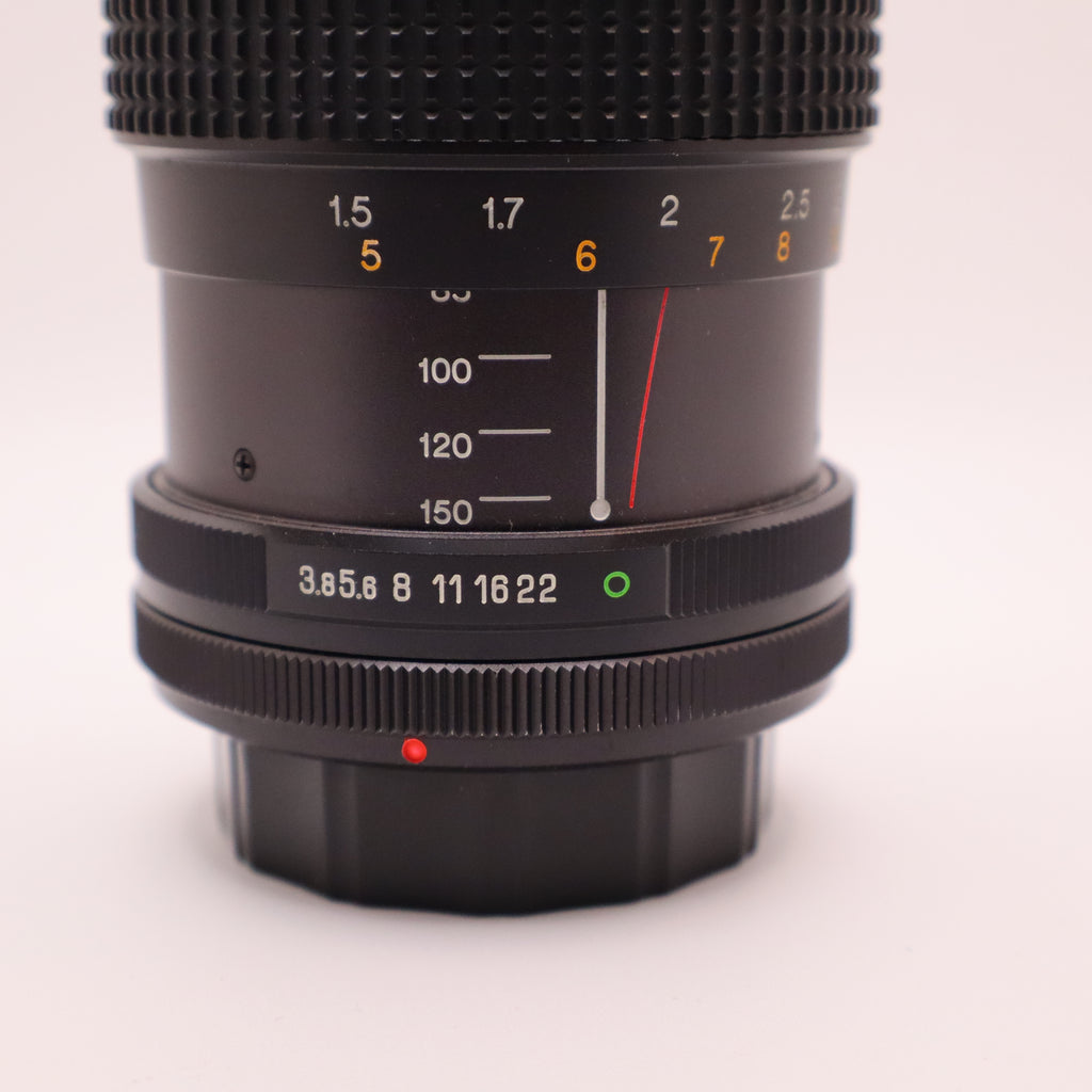 Camera lens with focus scale and aperture settings on a light pink background