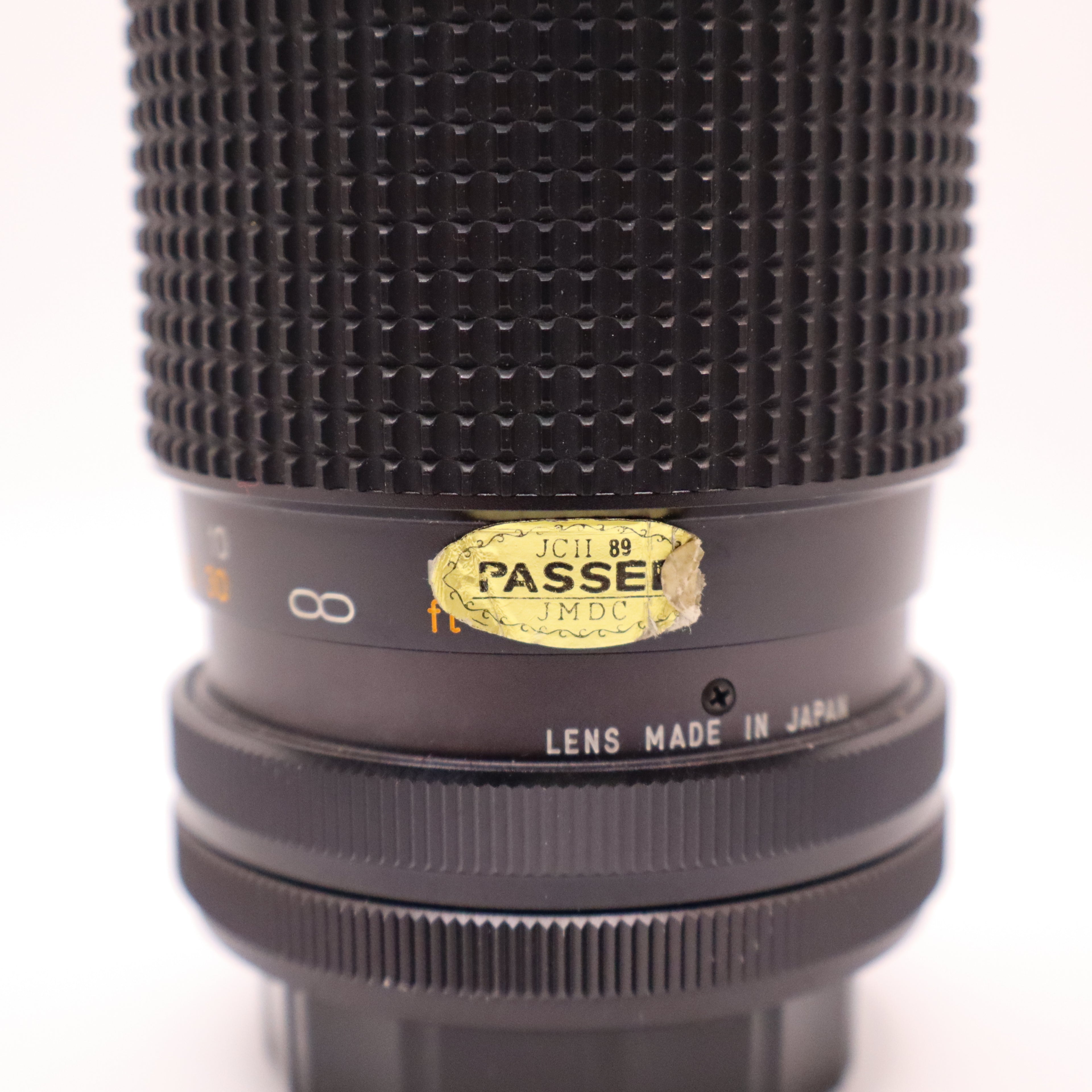 Close-up of a camera lens with 'Passei' branding on a white background