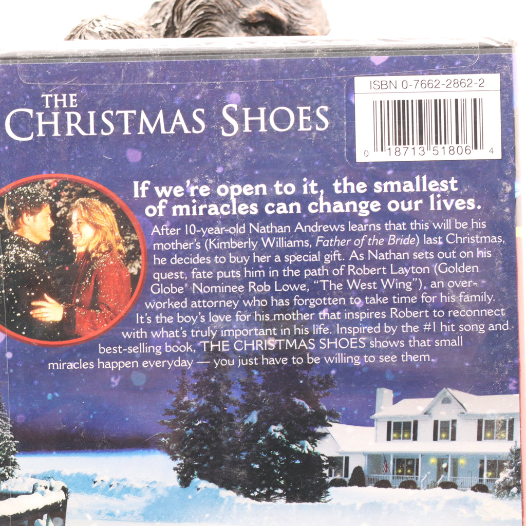 Back cover of 'The Christmas Shoes' book with a snowy scene and couple, featuring a barcode.