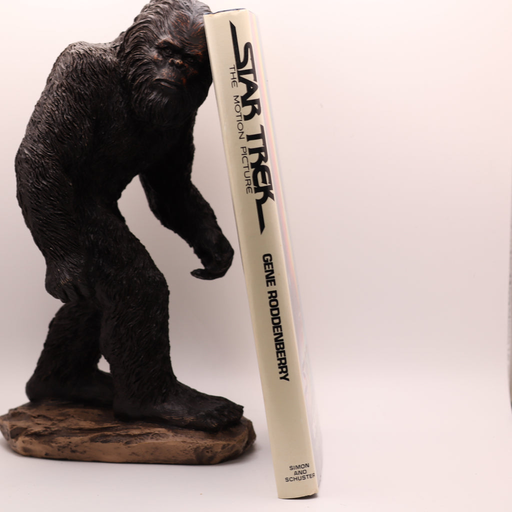 Gorilla figurine holding a 'Star Trek' book on a white background