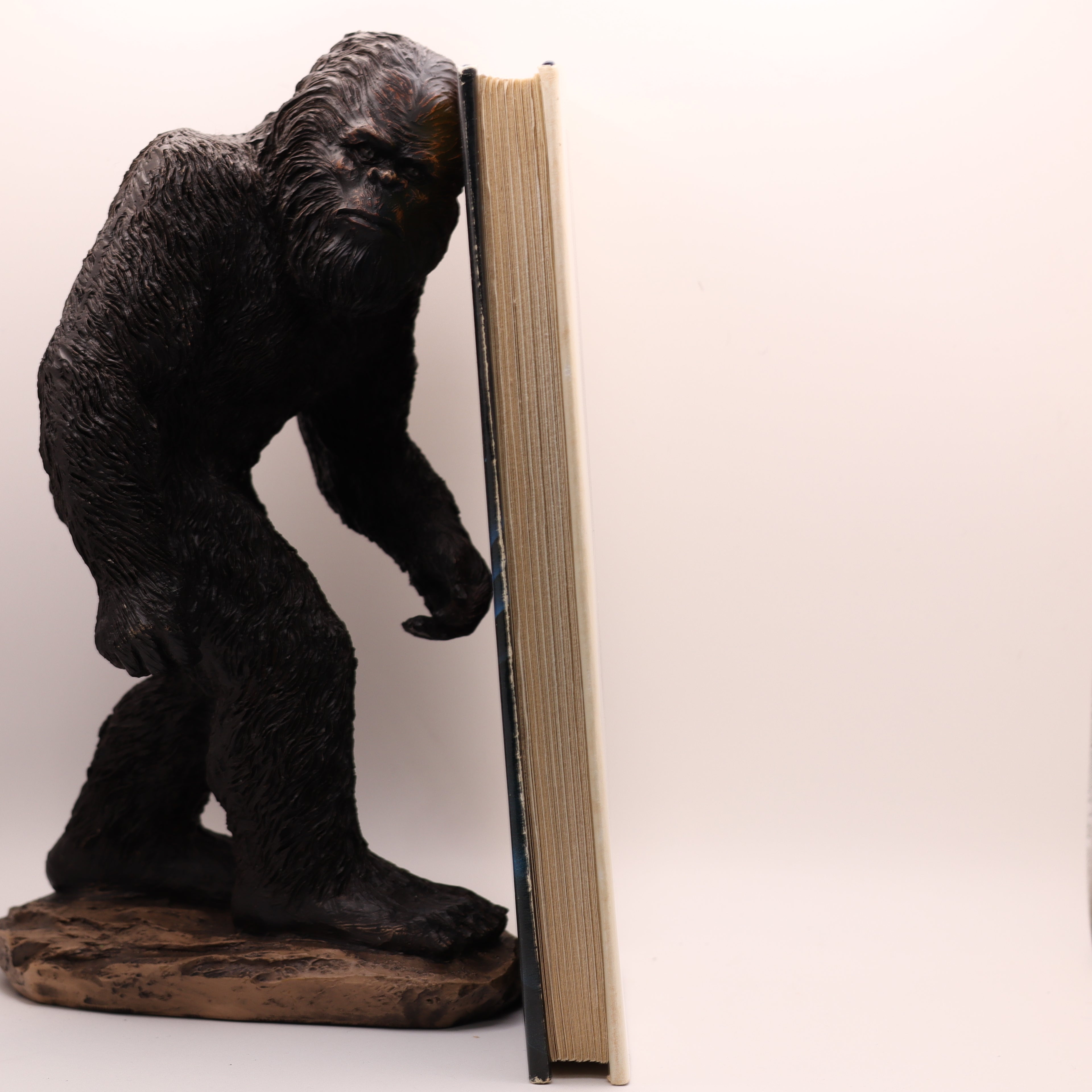 Gorilla-shaped bookend holding open a book on a white background