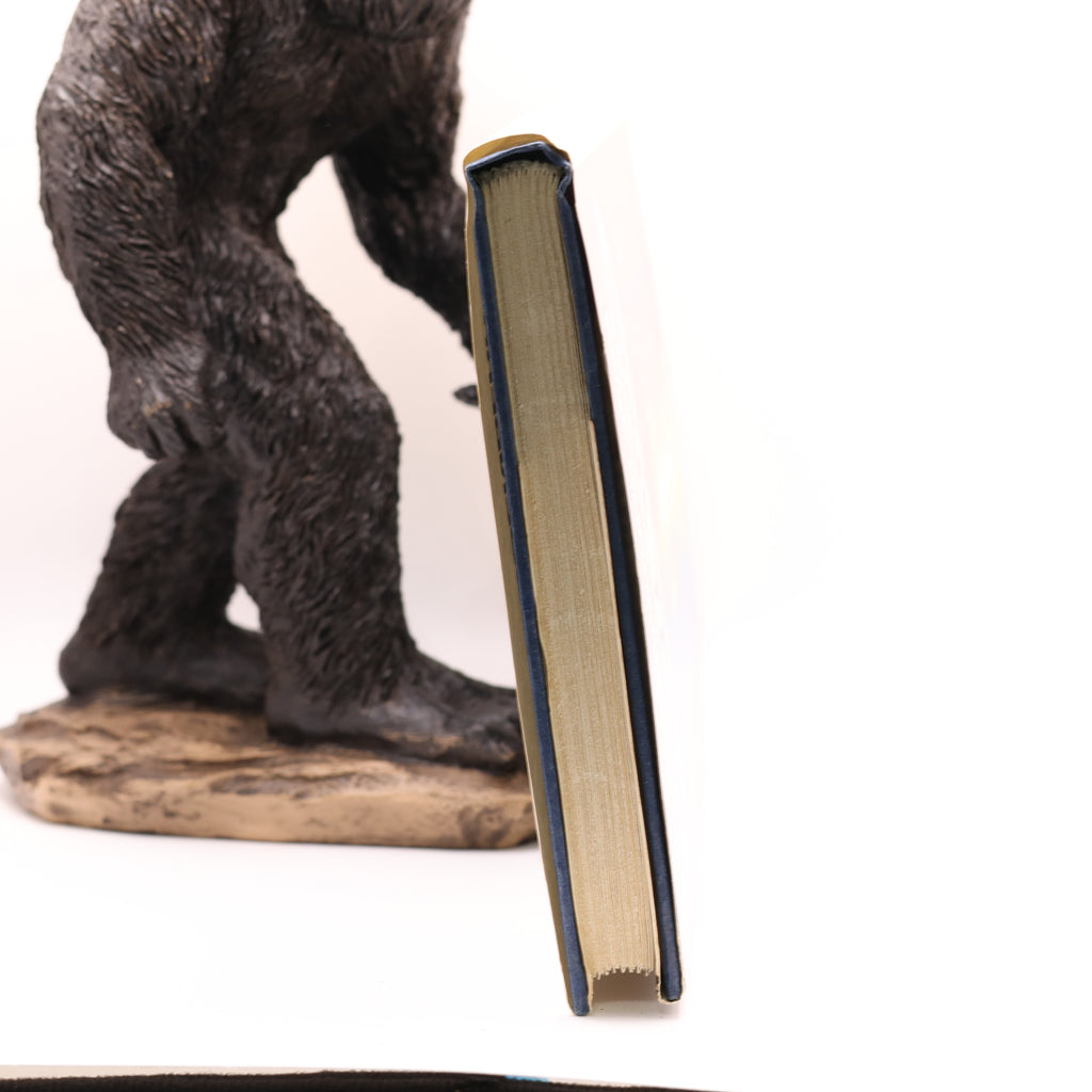 Statue of a large humanoid creature next to an open book on a white background