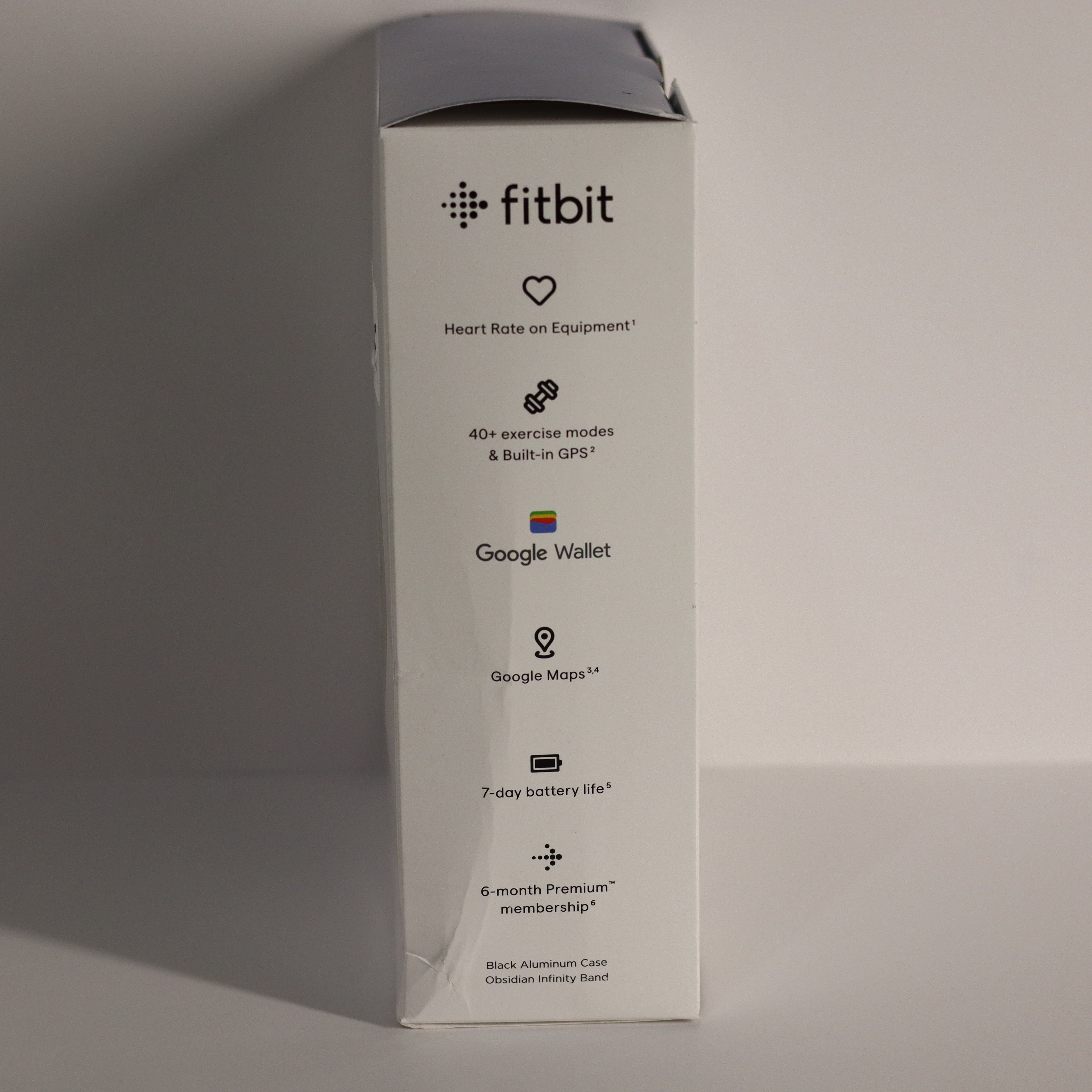 Fitbit product packaging with features listed on a gray background