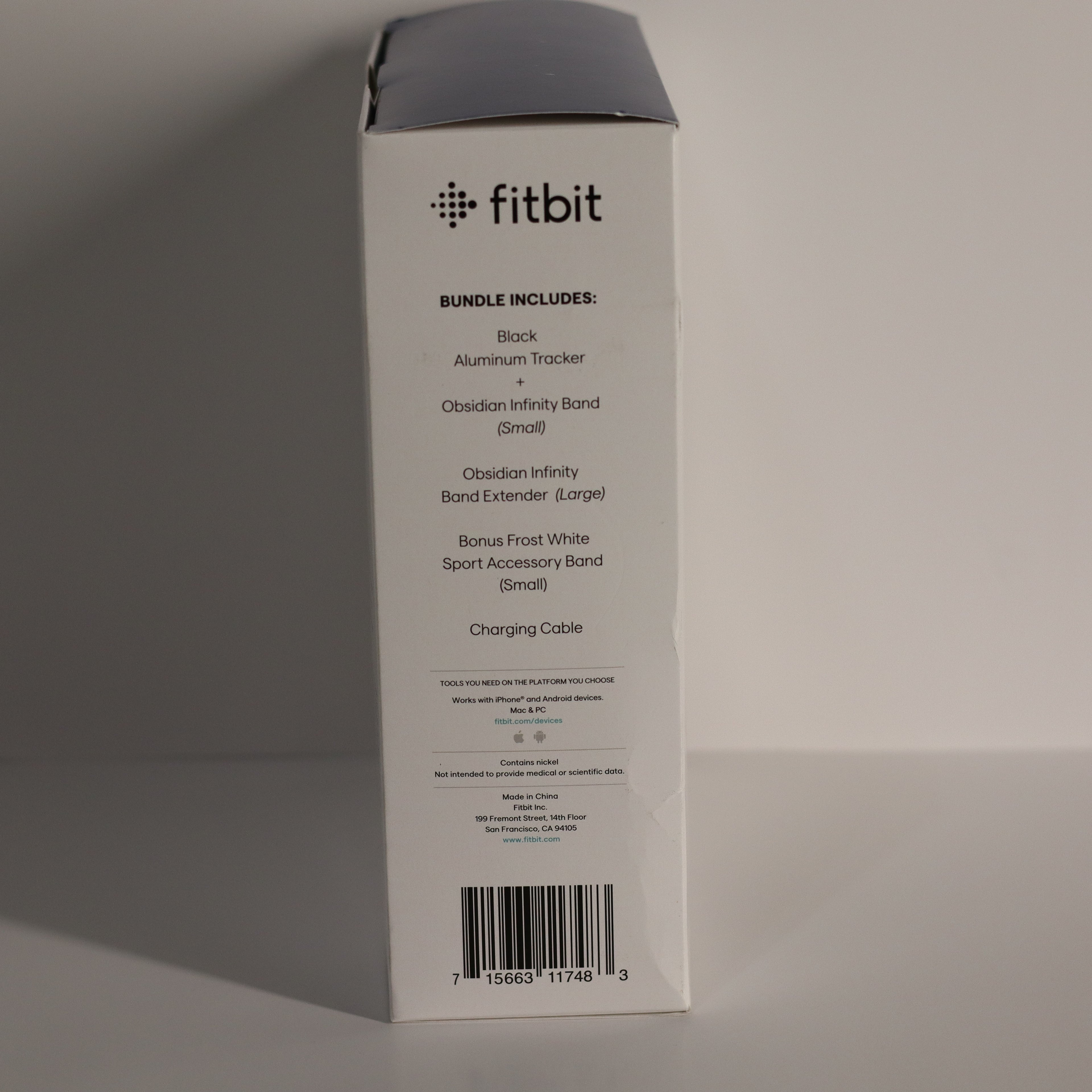 Fitbit product packaging box with item list on a gray background
