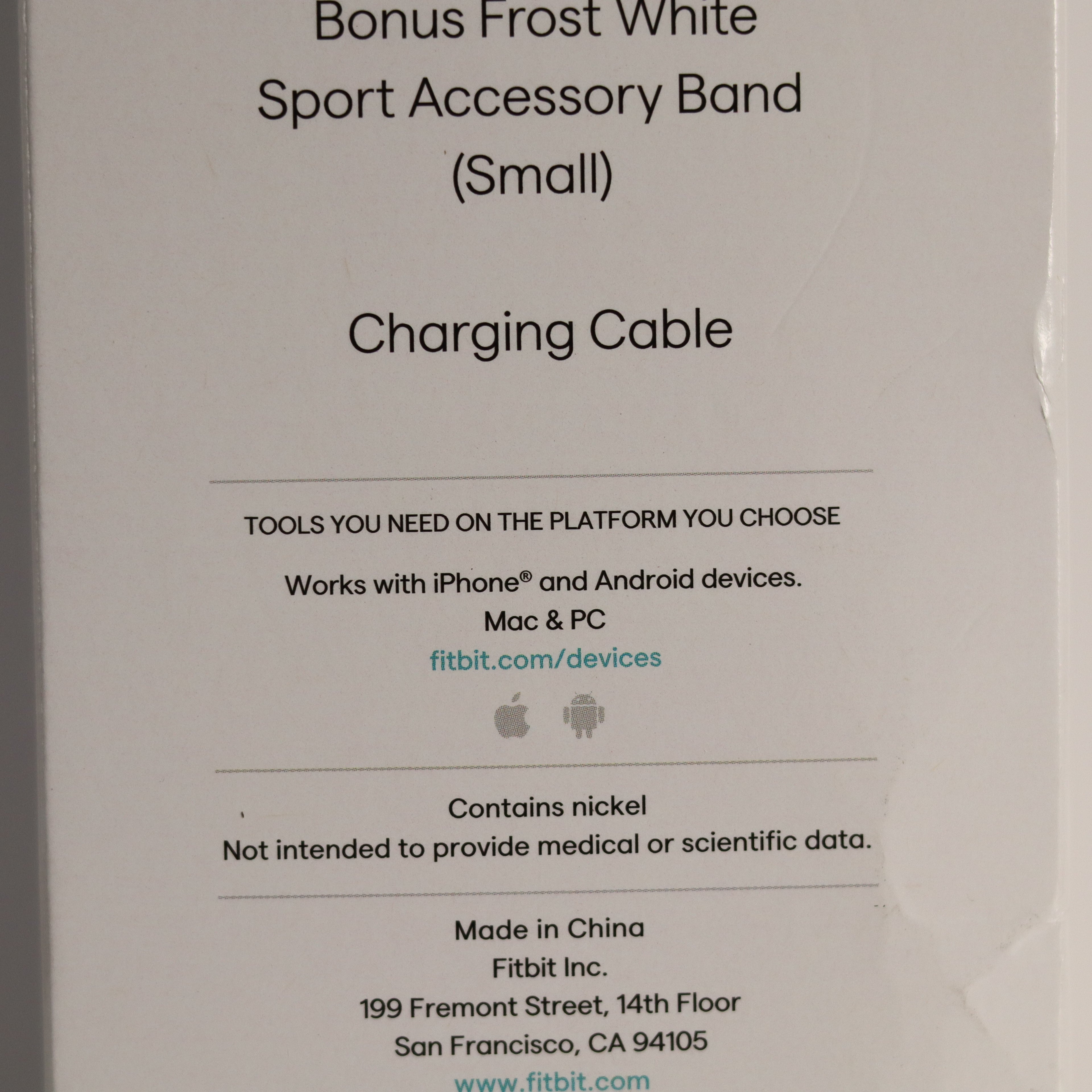 Fitbit accessory packaging with text about a bonus Frost White Sport Accessory Band and charging cable.