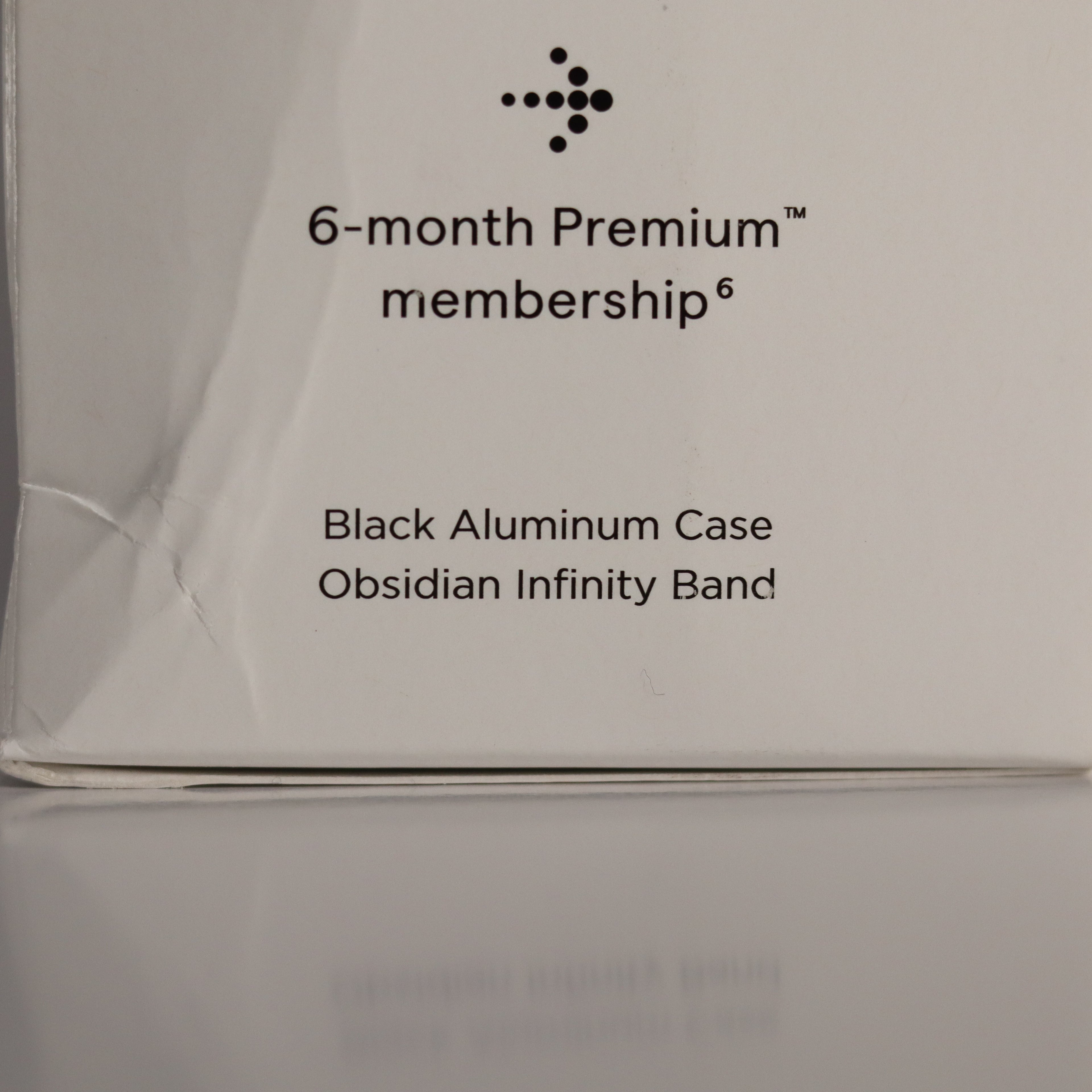 Product packaging with text about a 6-month premium membership, black aluminum case, and obsidian infinity band.
