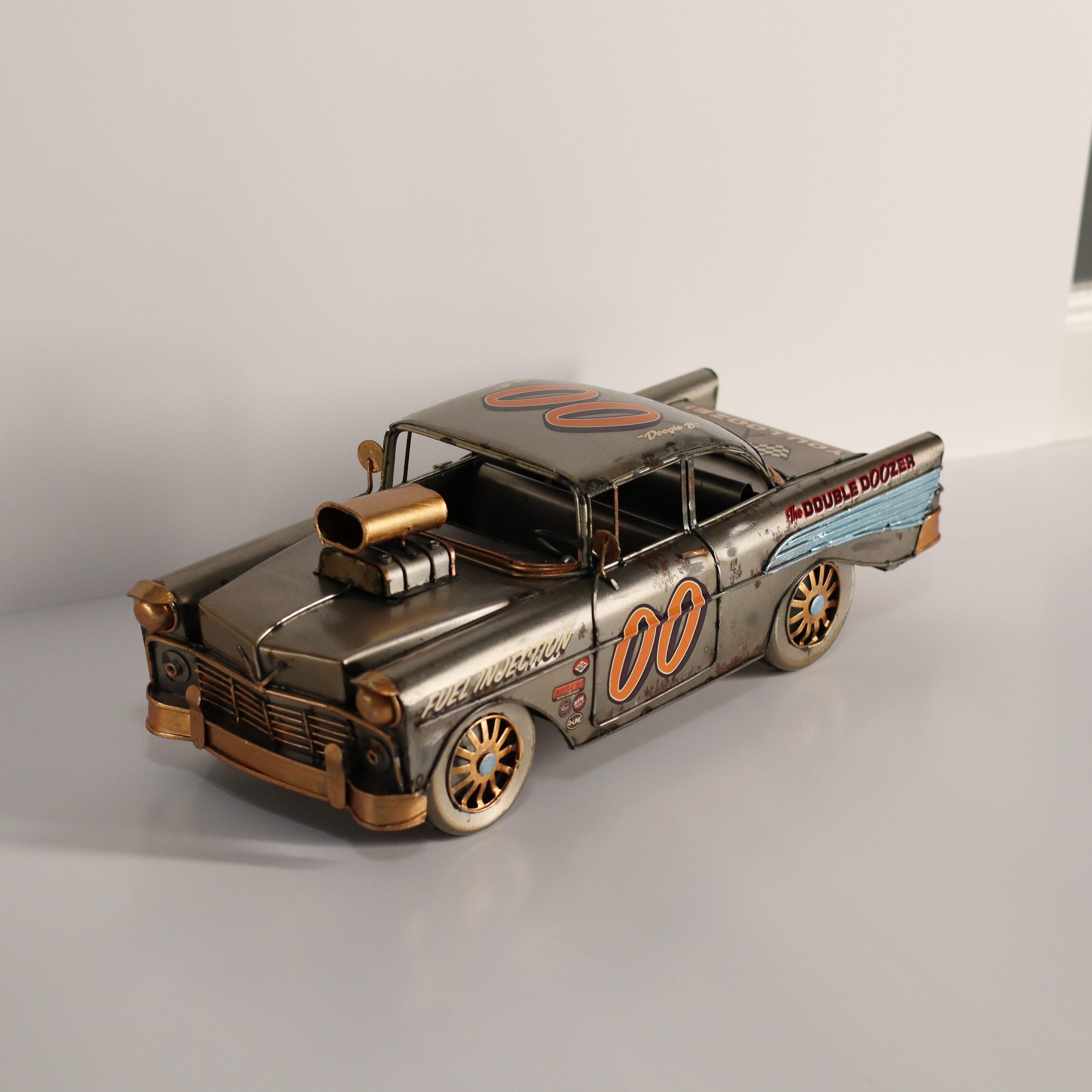 Metallic model of a vintage car with '00' on a white background