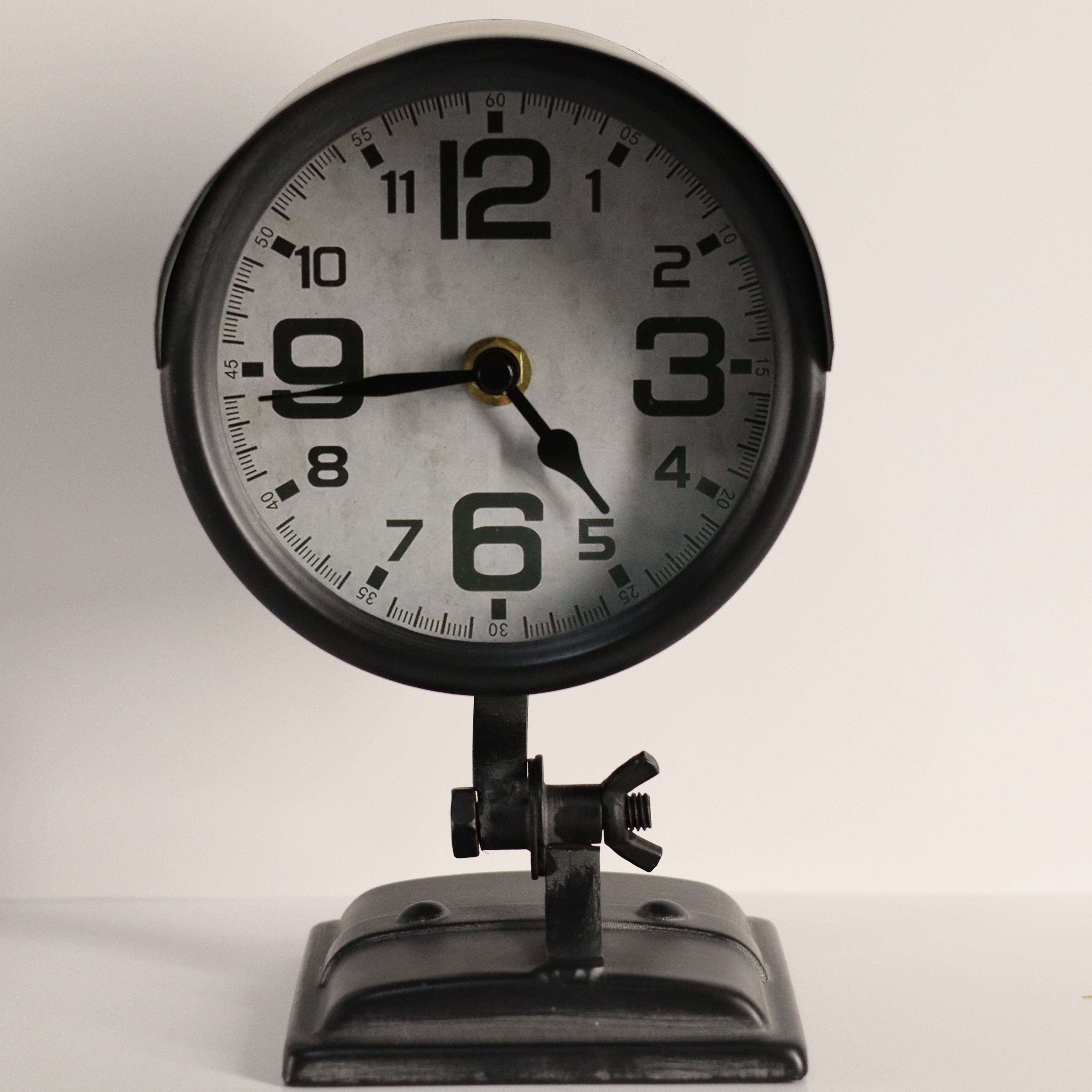 Vintage-style clock with black frame and white face on a light gray background