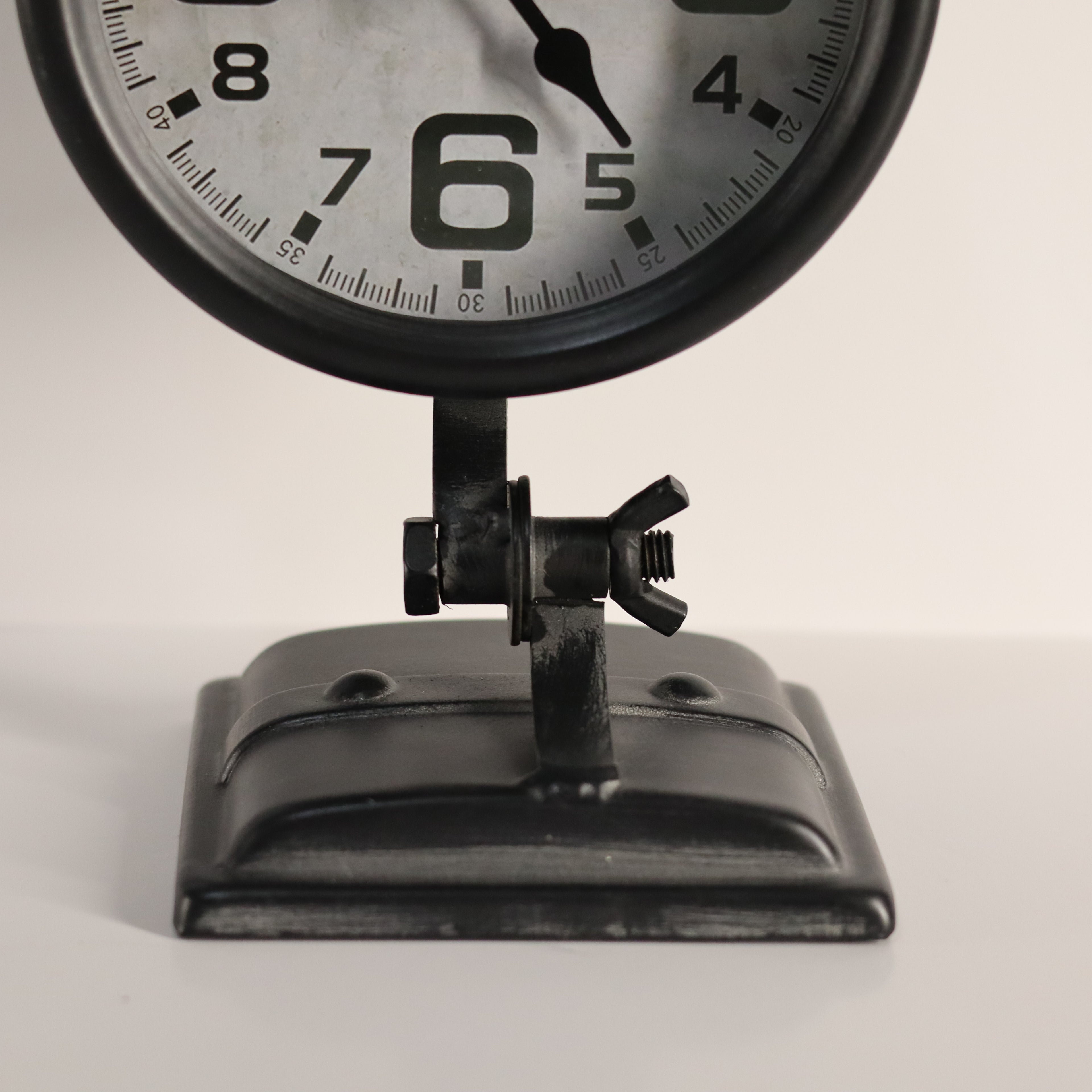 Vintage-style clock with black frame and white face on a light gray background