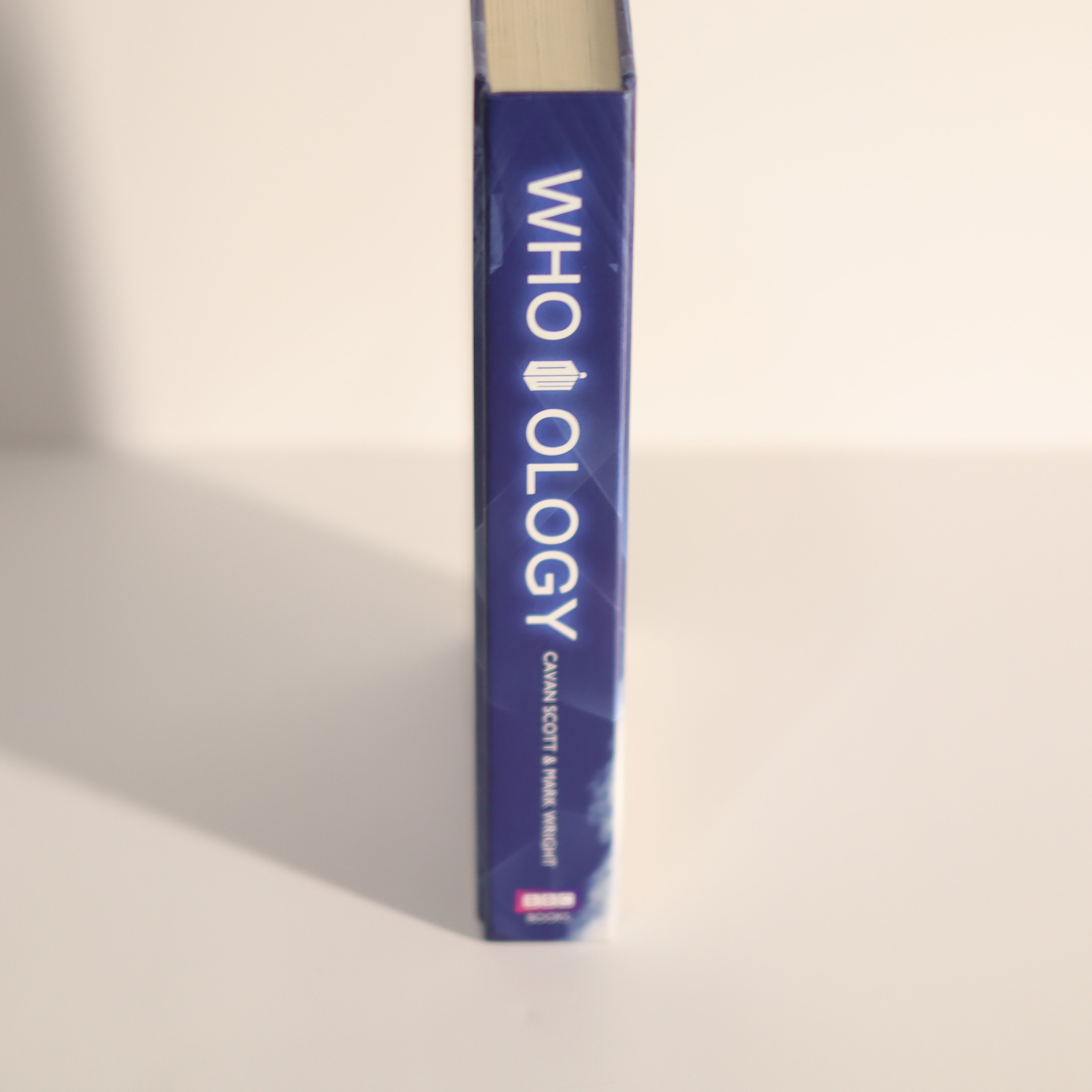 Blue book titled 'WHO OLOGY' on a beige background