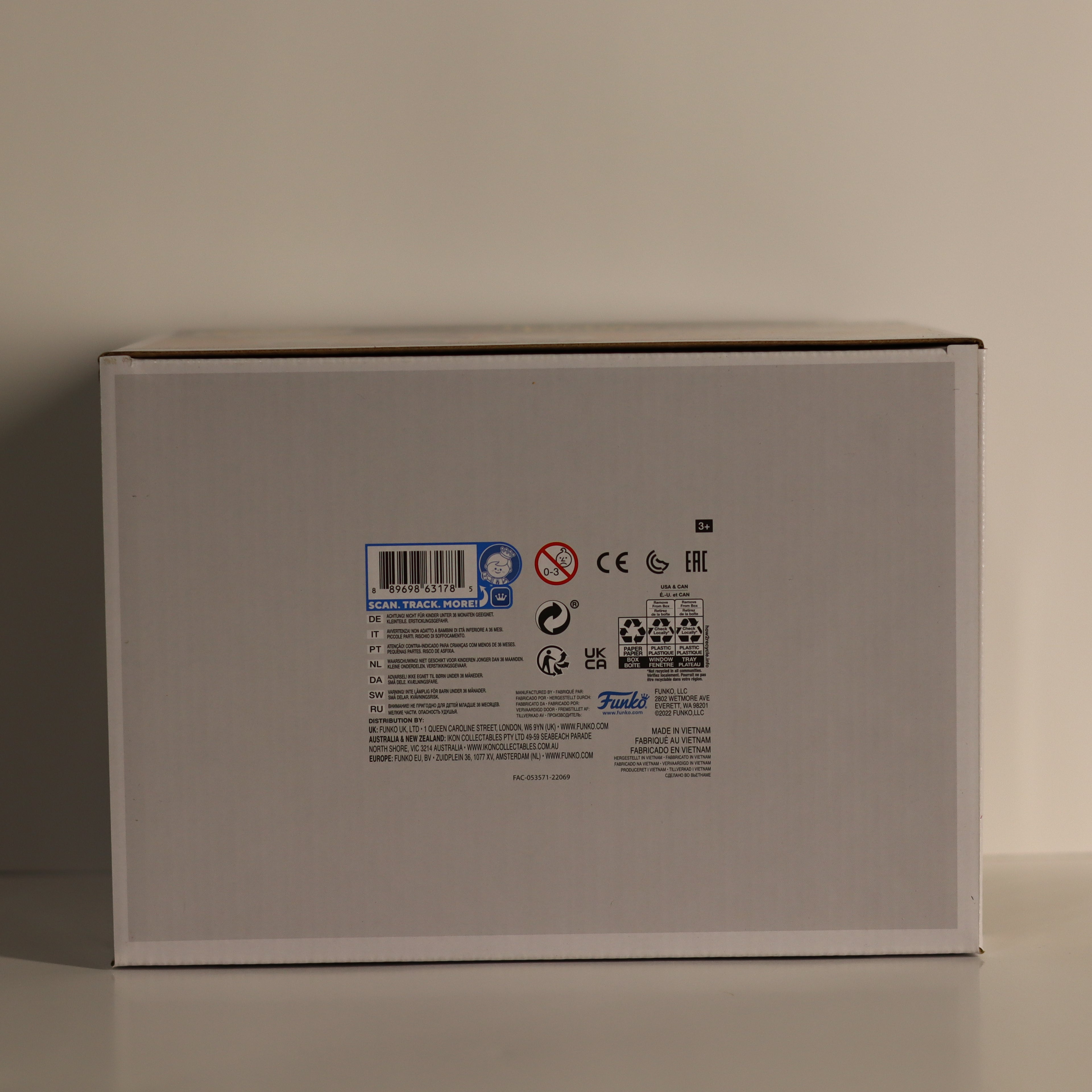Back view of a gray product box with labels and symbols on a beige background