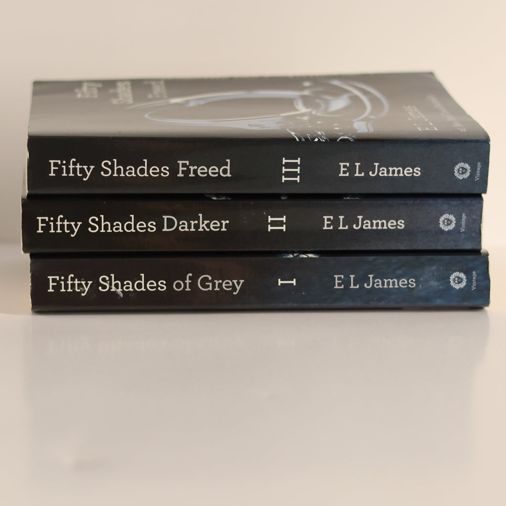 Three books by E L James titled 'Fifty Shades of Grey', 'Fifty Shades Darker', and 'Fifty Shades Freed' stacked on a light background.