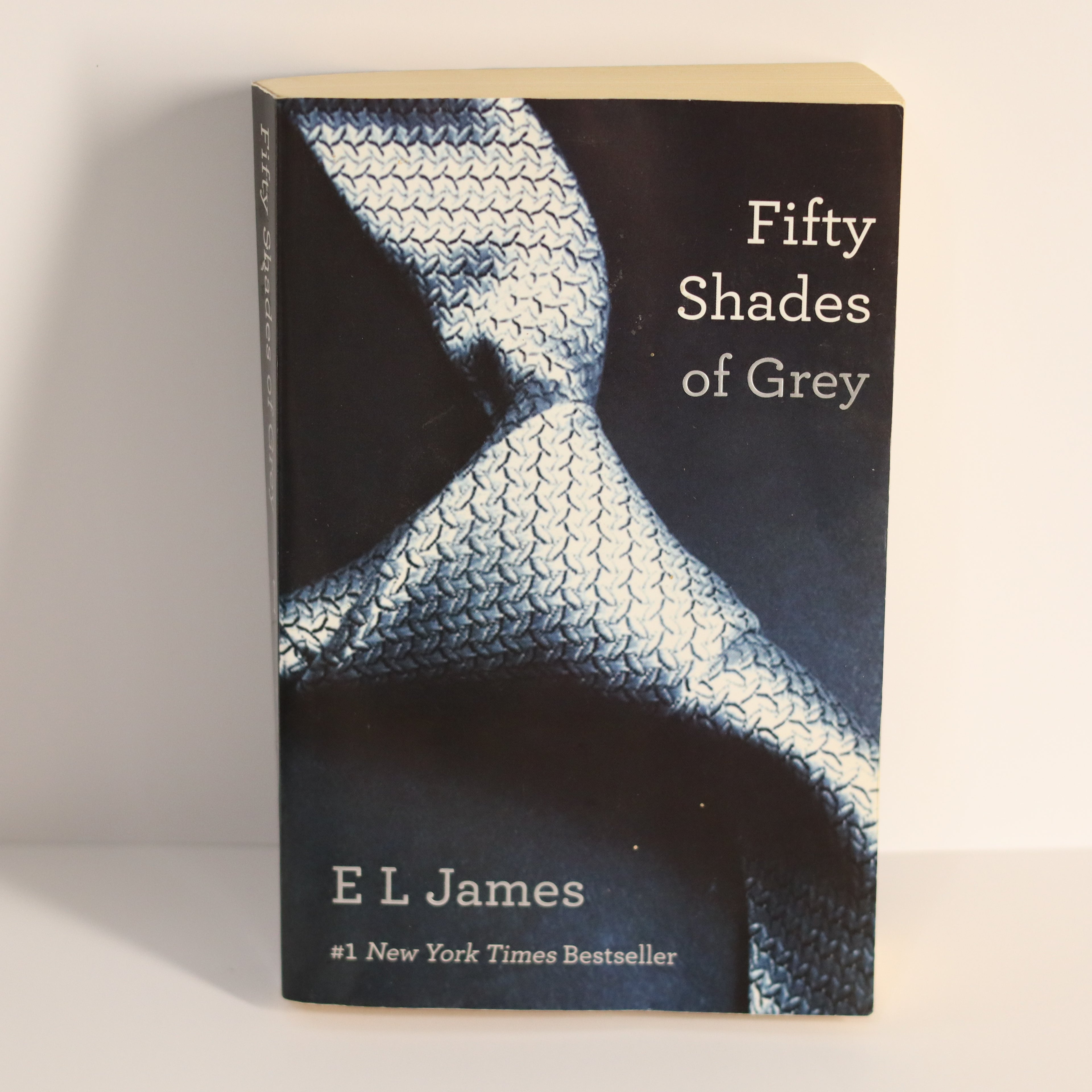 Book titled 'Fifty Shades of Grey' by E L James on a plain background