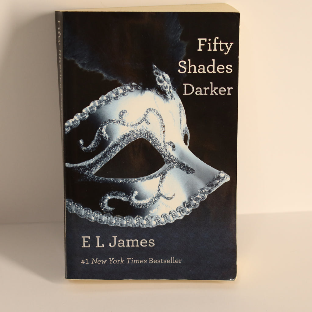 Book titled 'Fifty Shades Darker' by E L James with a black cover and silver mask design.