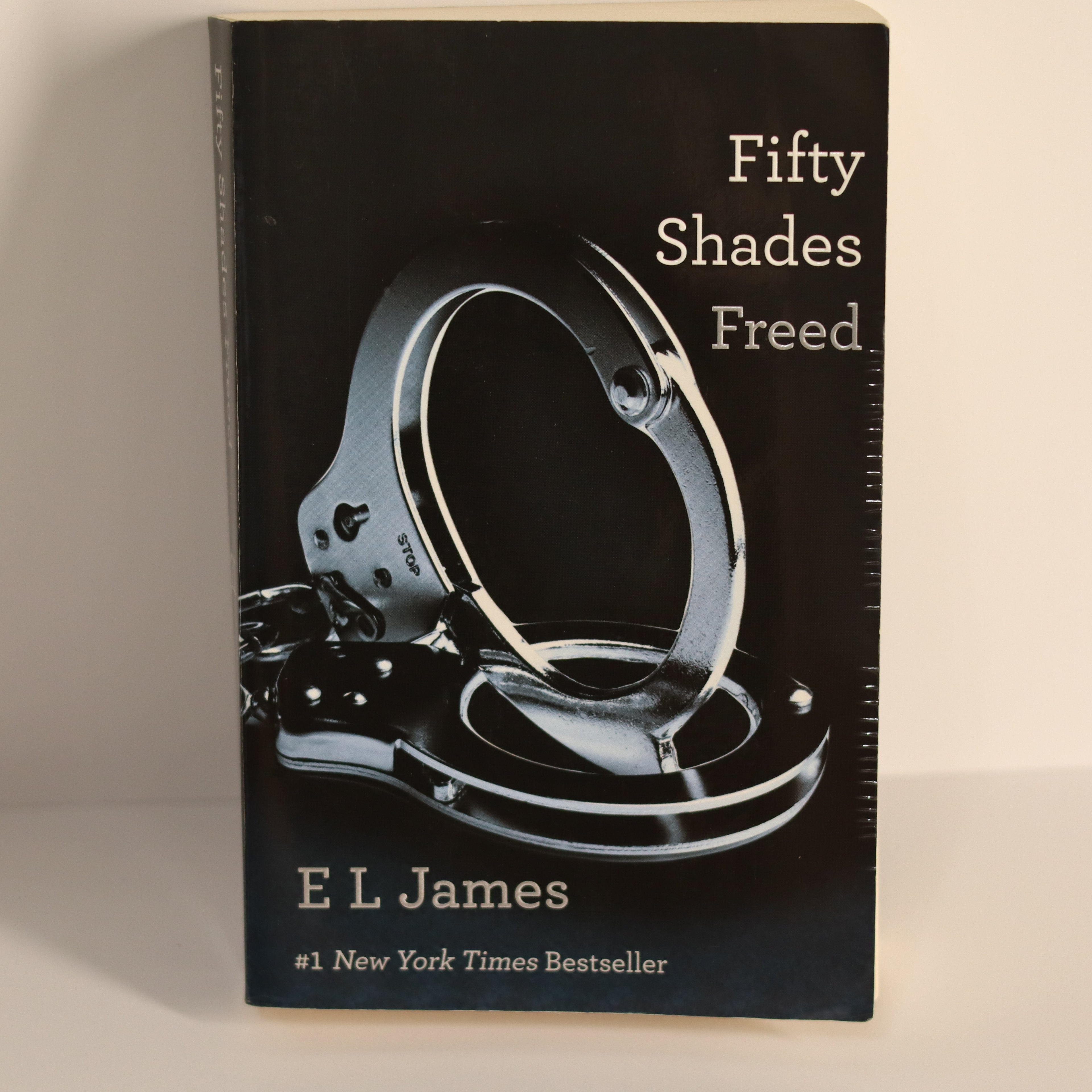 Book cover of 'Fifty Shades Freed' with handcuffs on a black background