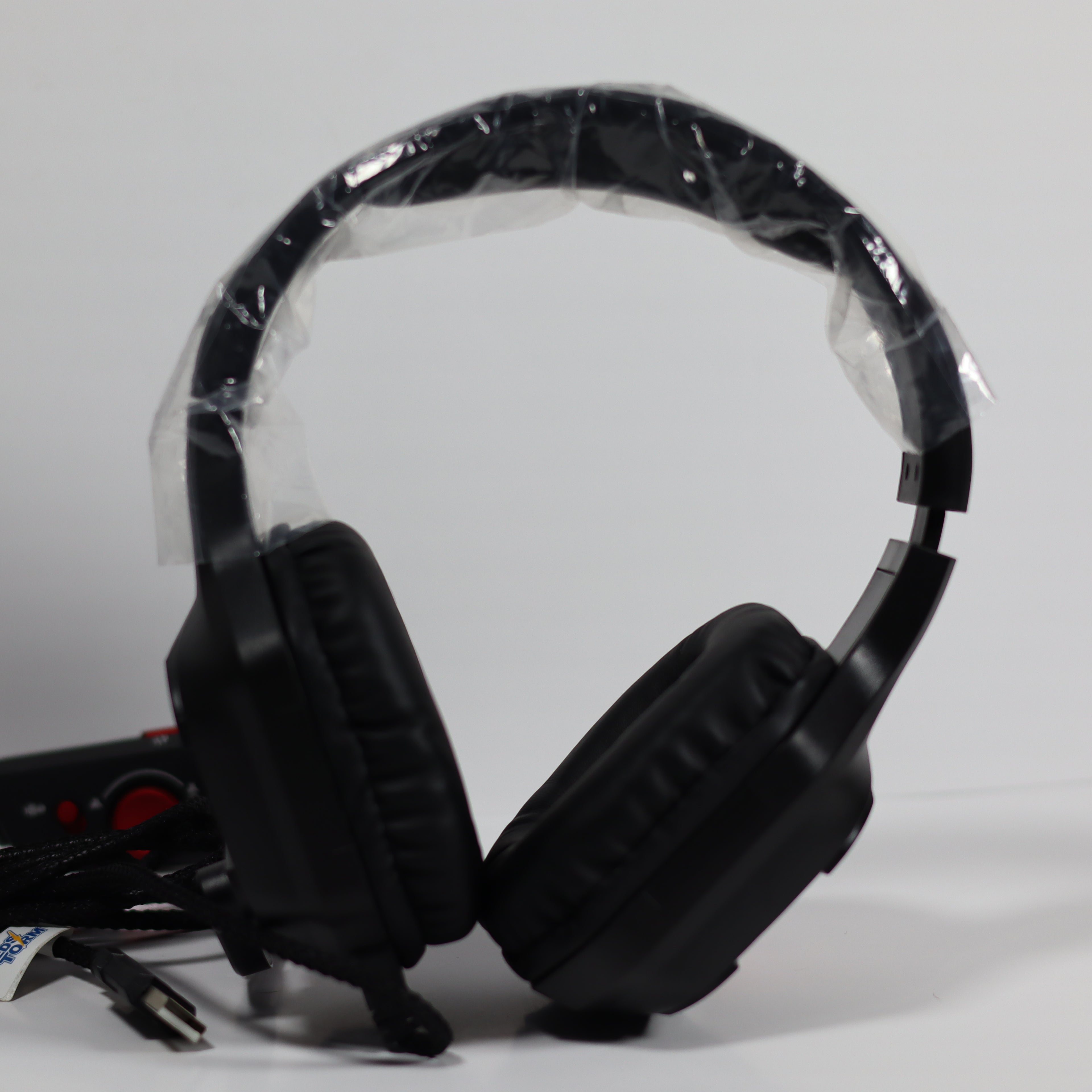 Black gaming headset with plastic wrap on a gray background