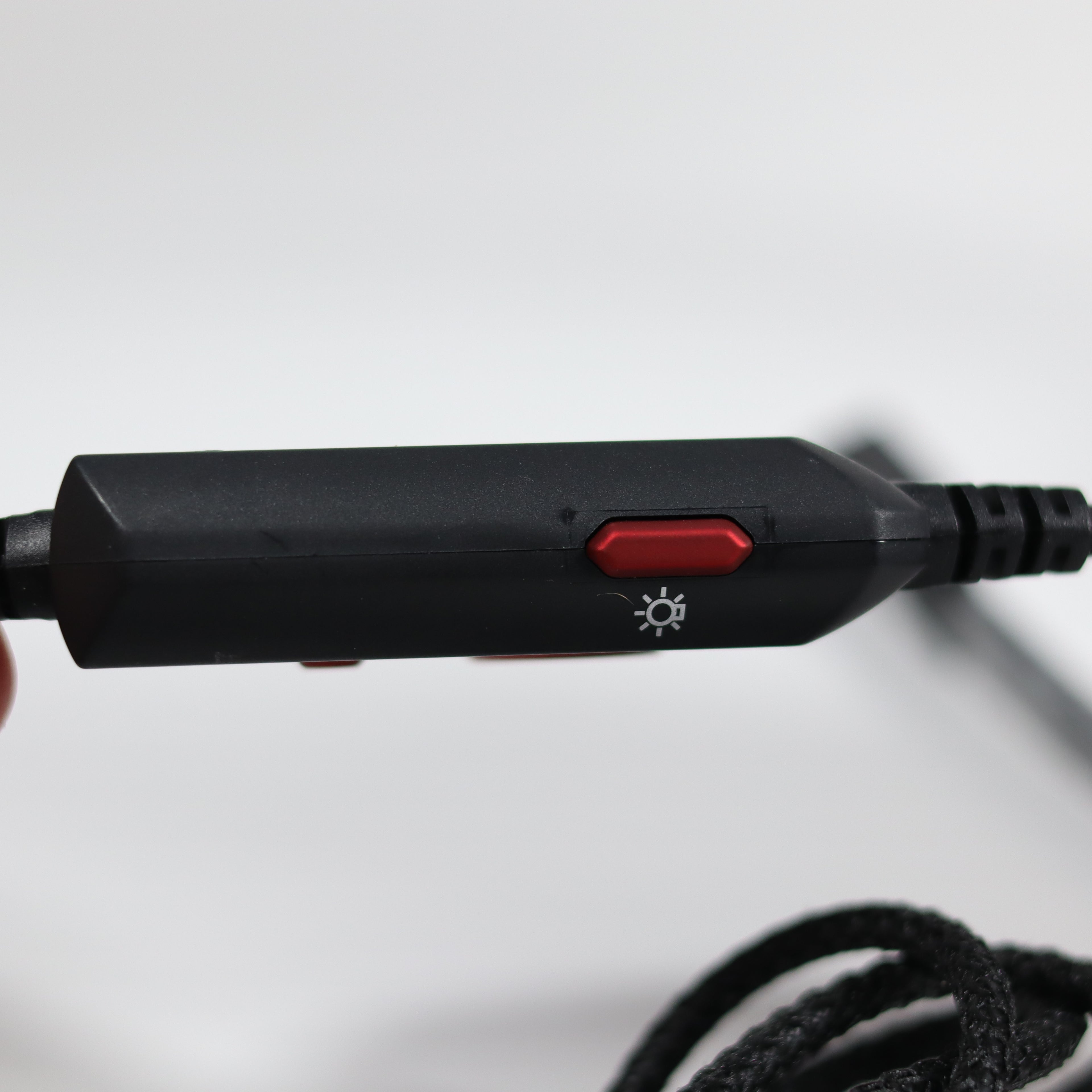 Black electronic device with a red button on a white background