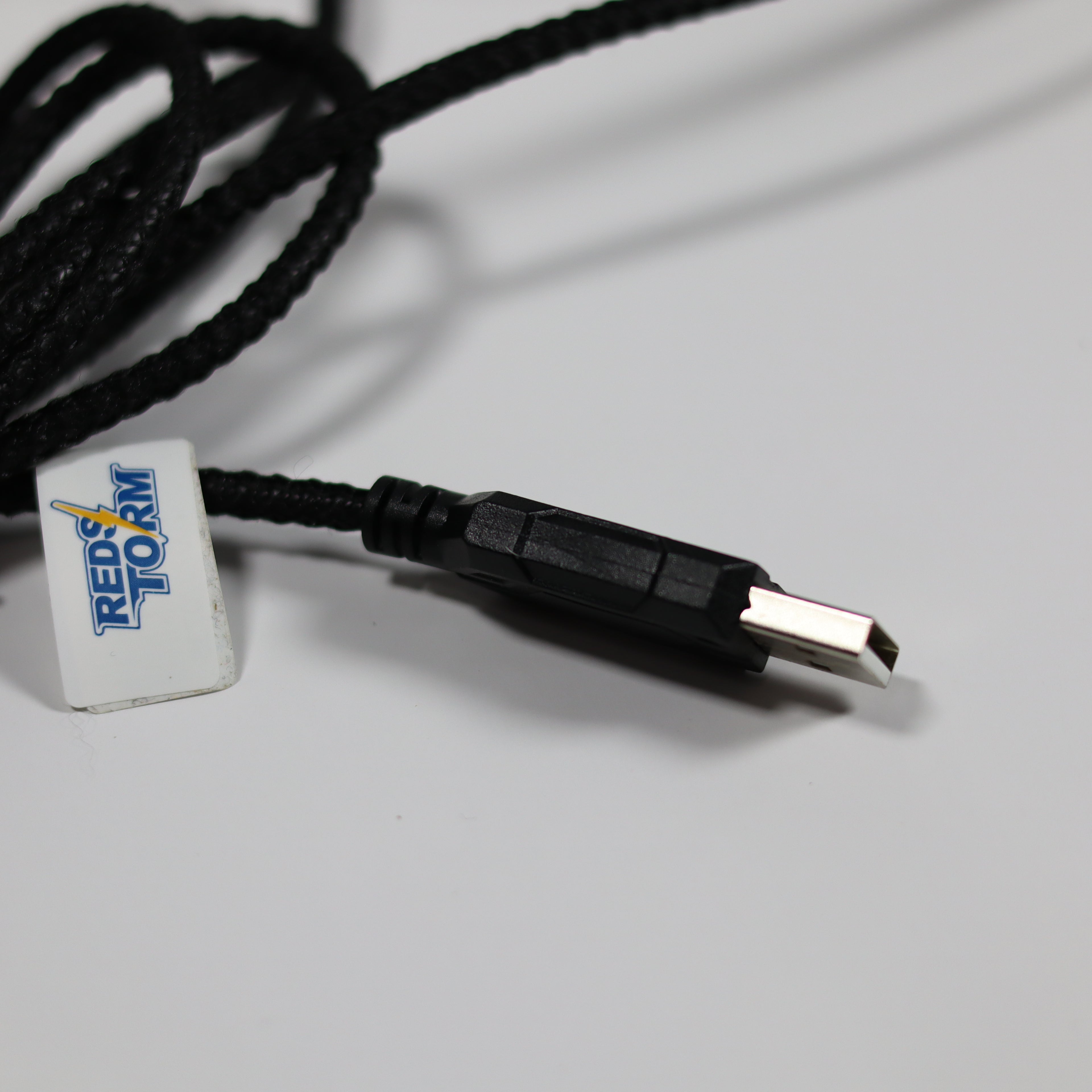 Black USB cable with a white connector featuring a logo on a gray background