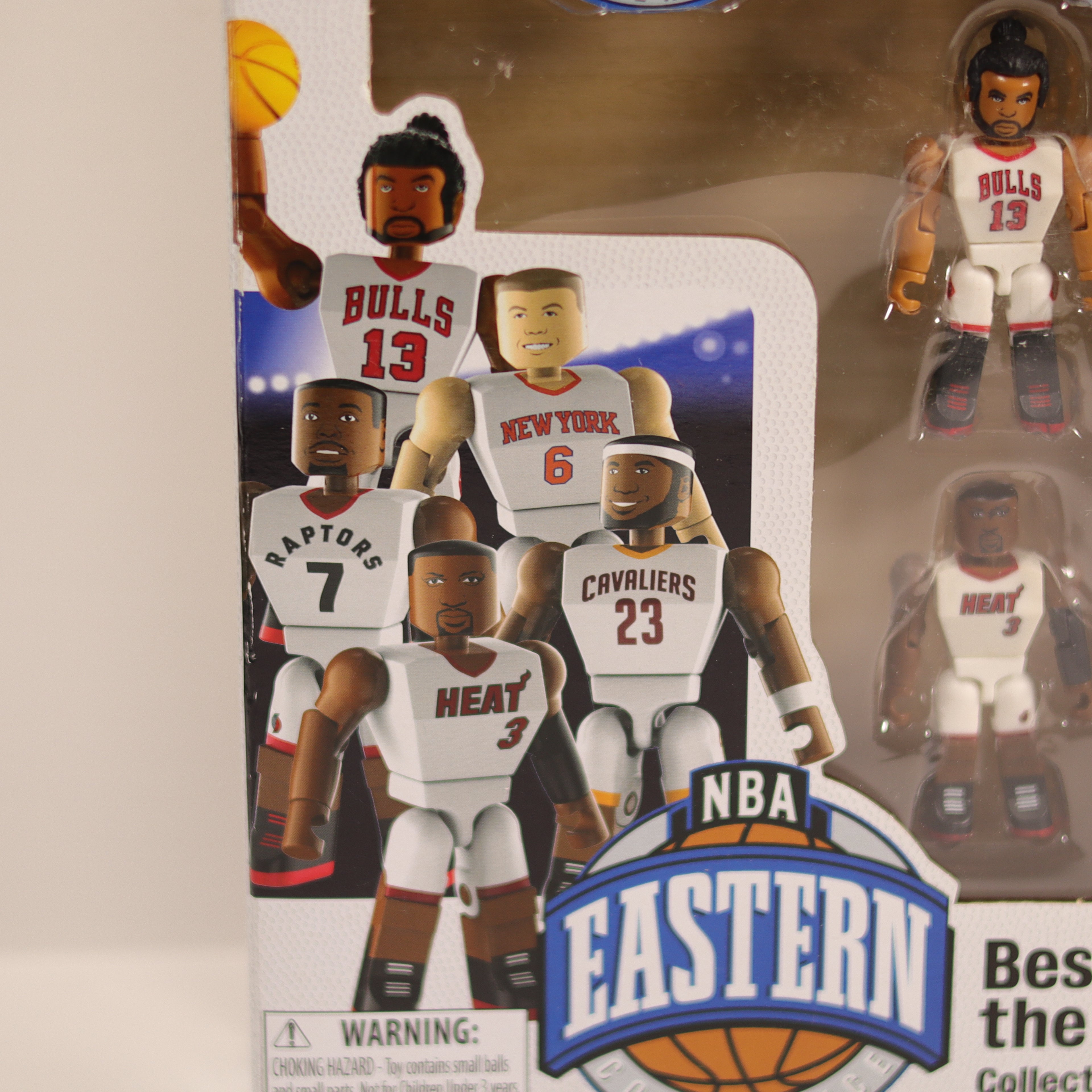 Packaged NBA action figures with player cards on a beige background