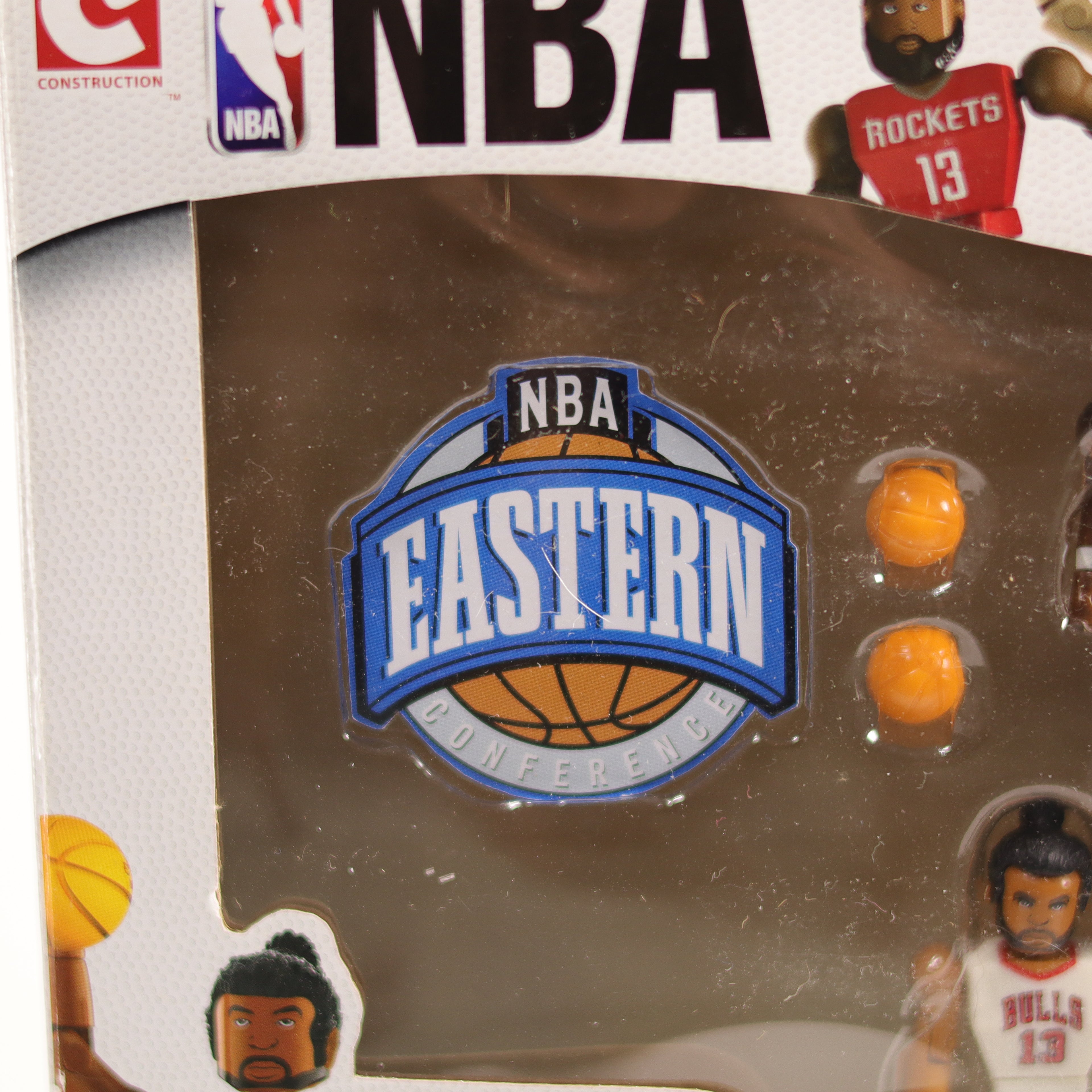 NBA toy set packaging with basketballs and player figures on a reflective surface.