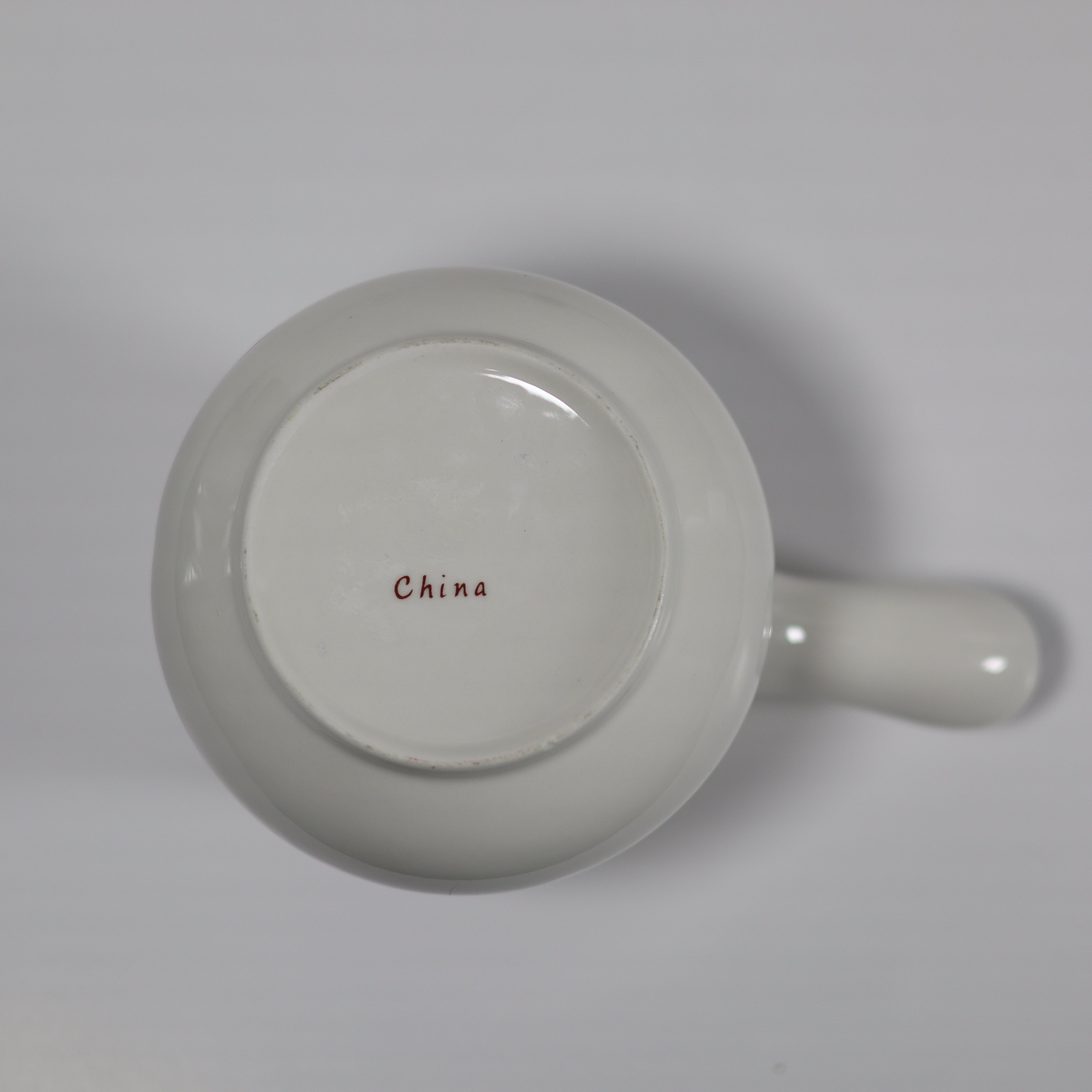 White ceramic mug with 'China' printed on the bottom on a light gray background
