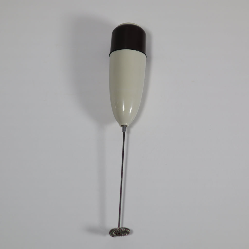 White and black handheld milk frother on a light gray background
