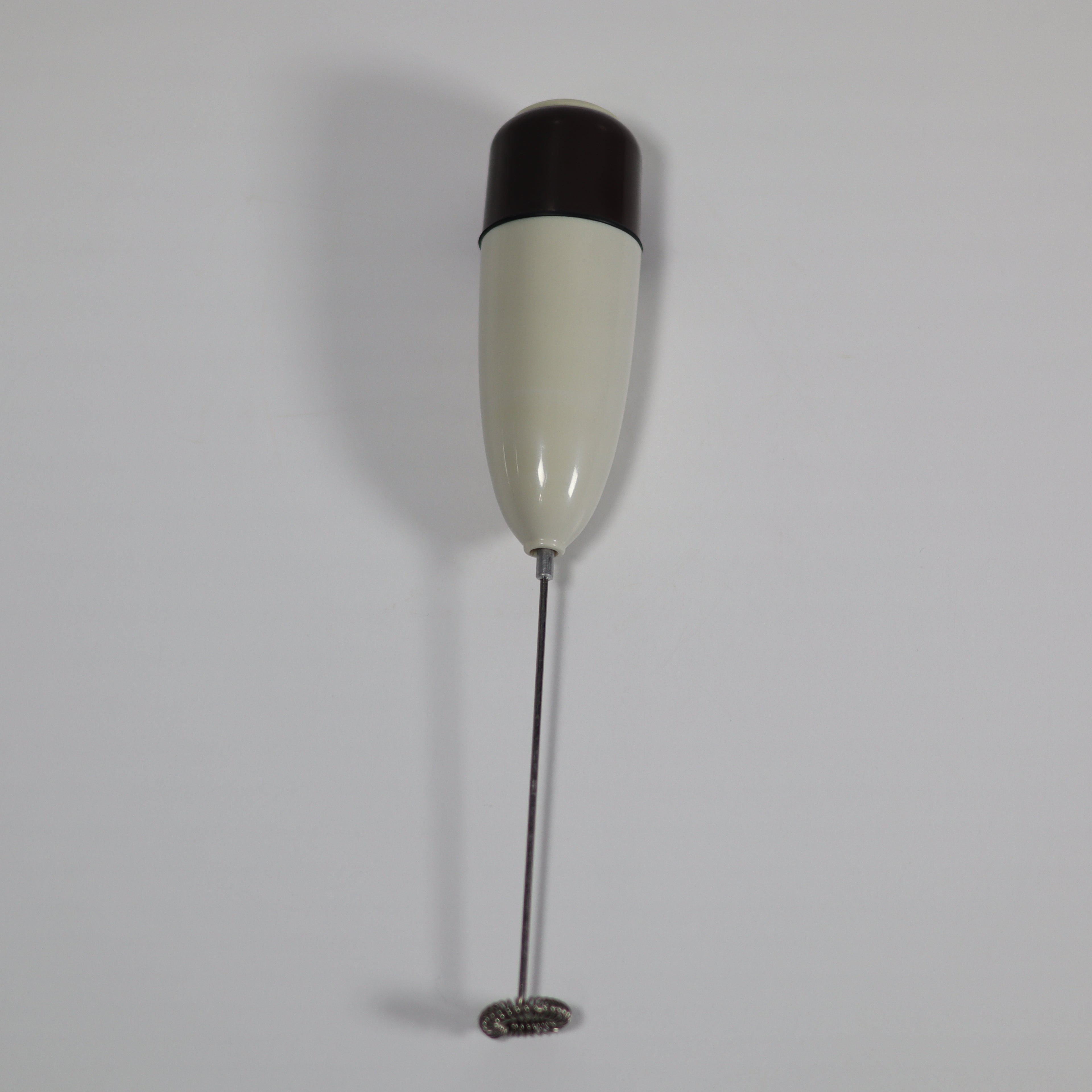 White and black handheld milk frother on a light gray background