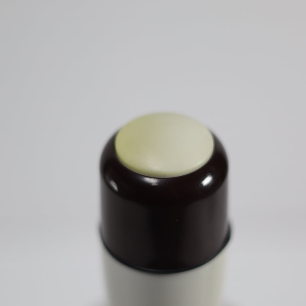 Black and white cylindrical container with a beige cap on a light gray background