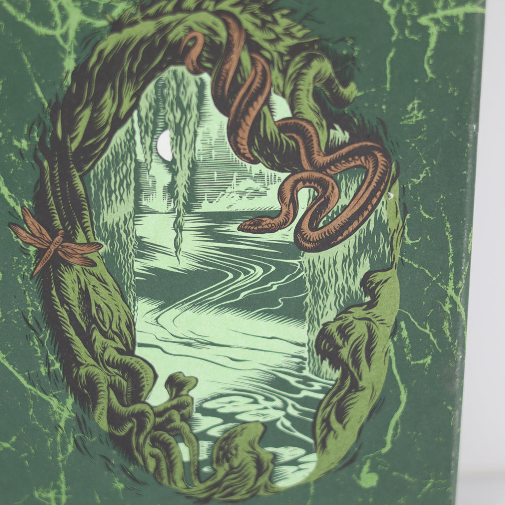 Illustration of a snake coiled around a wreath with a moonlit scene in the background.