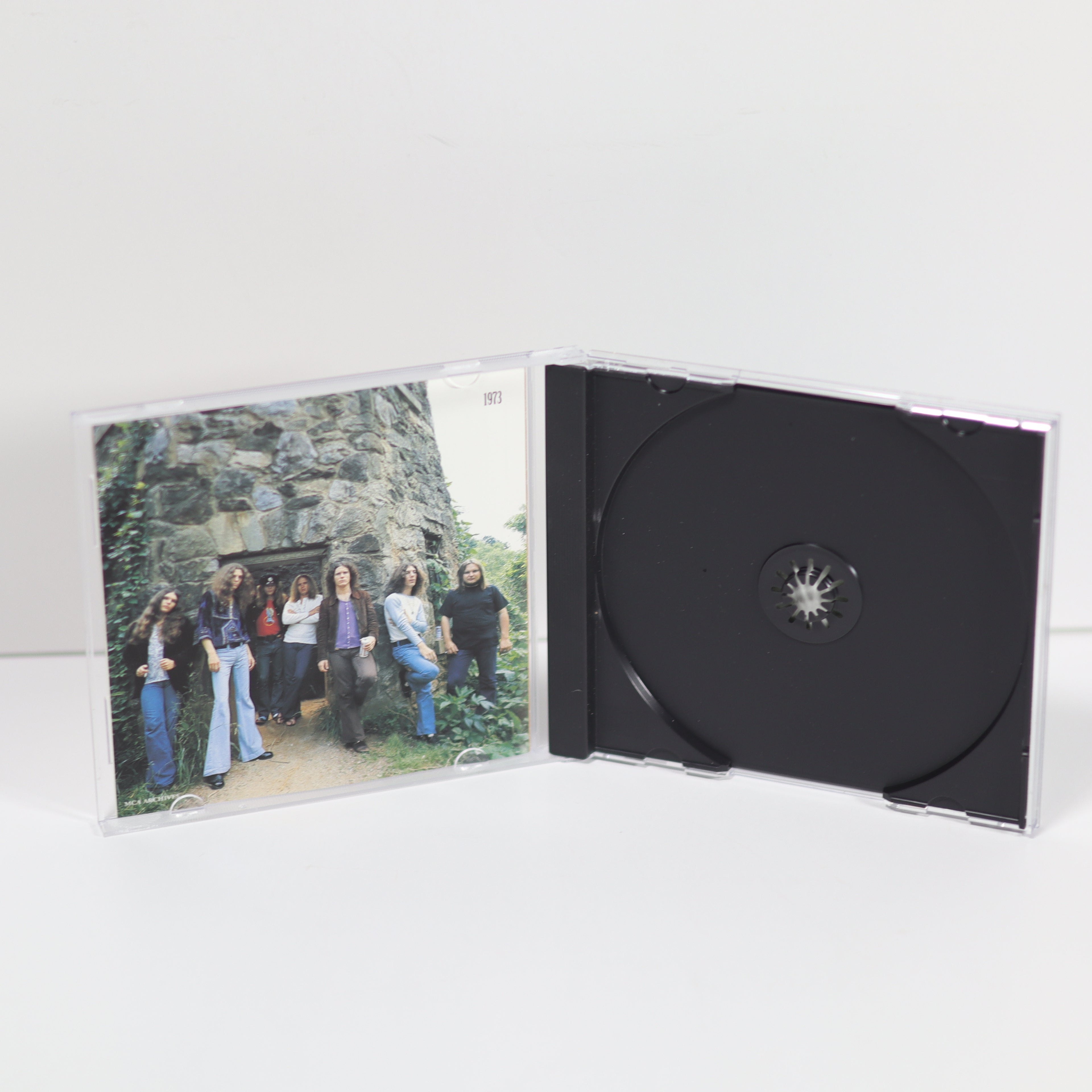 CD case with a photo of people on one side and a black disc on the other, on a white background