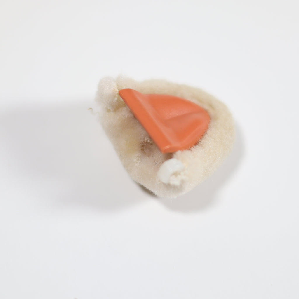 Small toy resembling a sheep with an orange carrot on a white background