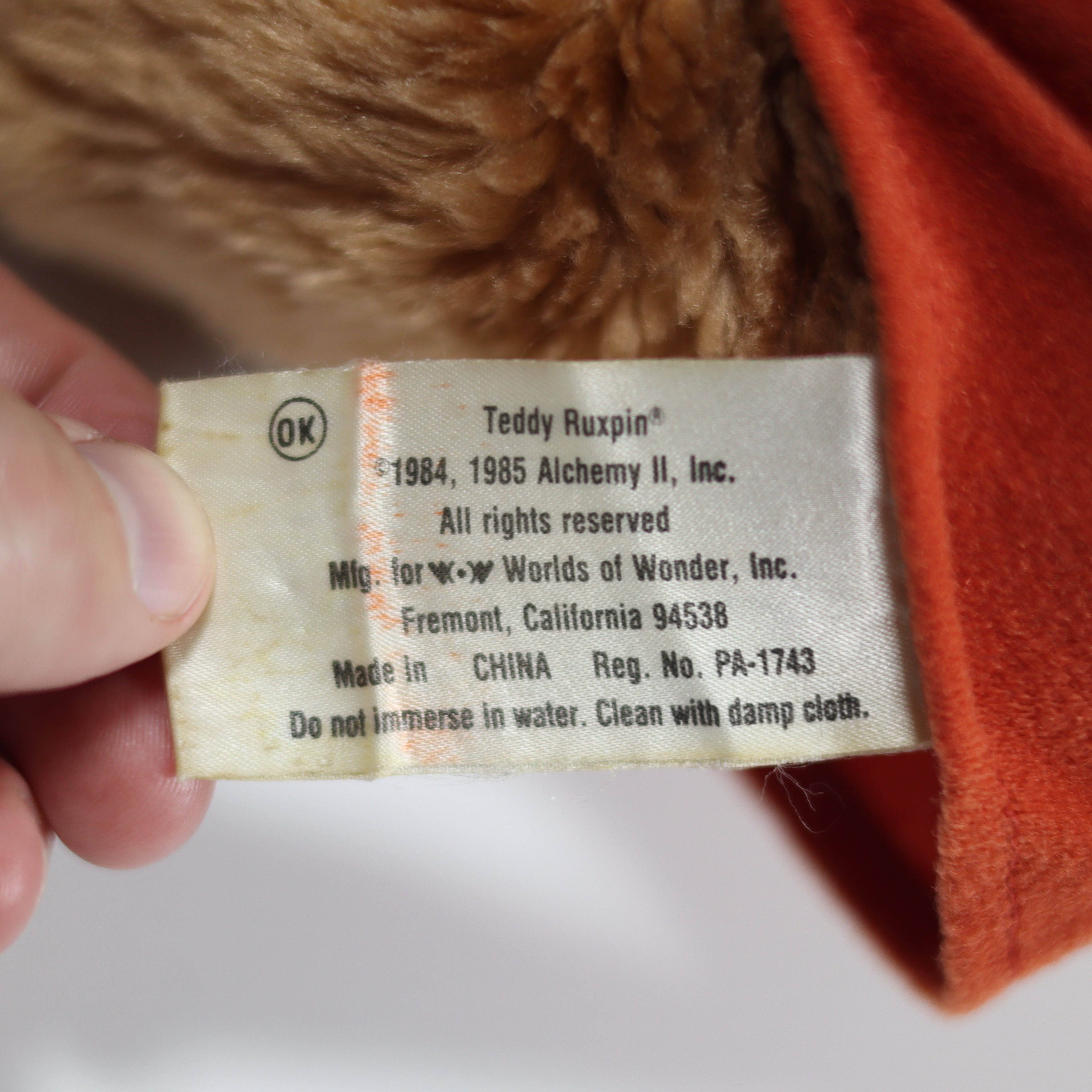 Close-up of a label on a teddy bear with text about rights and manufacturing details.