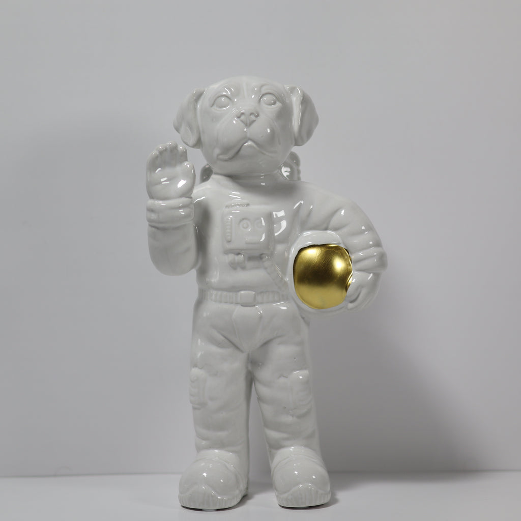 White ceramic dog figurine in astronaut costume with gold ball on gray background