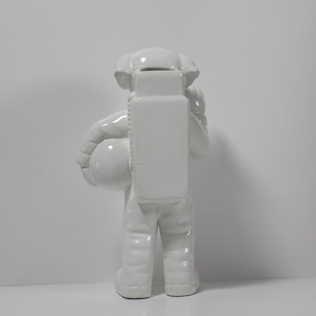 White ceramic monkey figurine holding a block on a light gray background