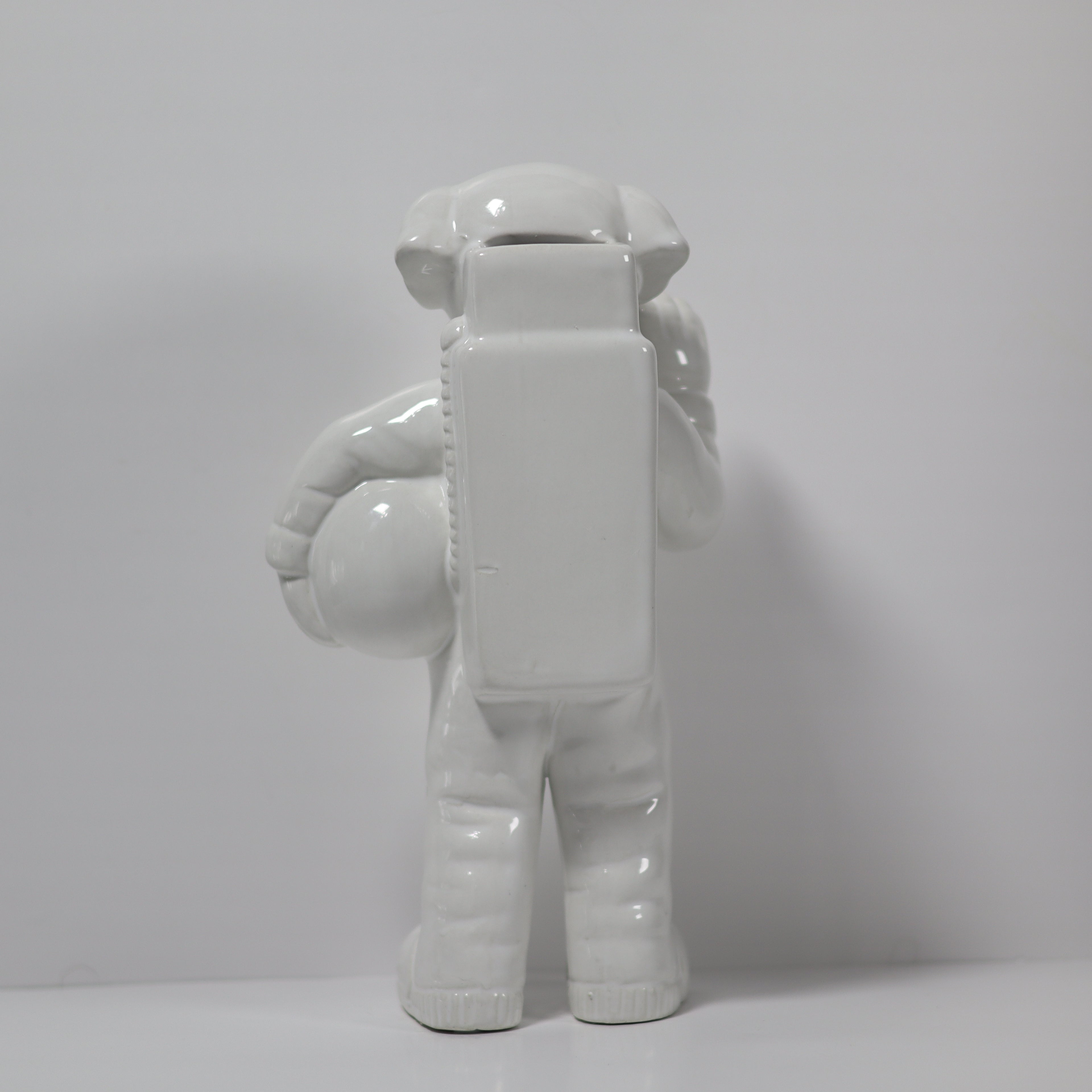White ceramic monkey figurine holding a block on a light gray background