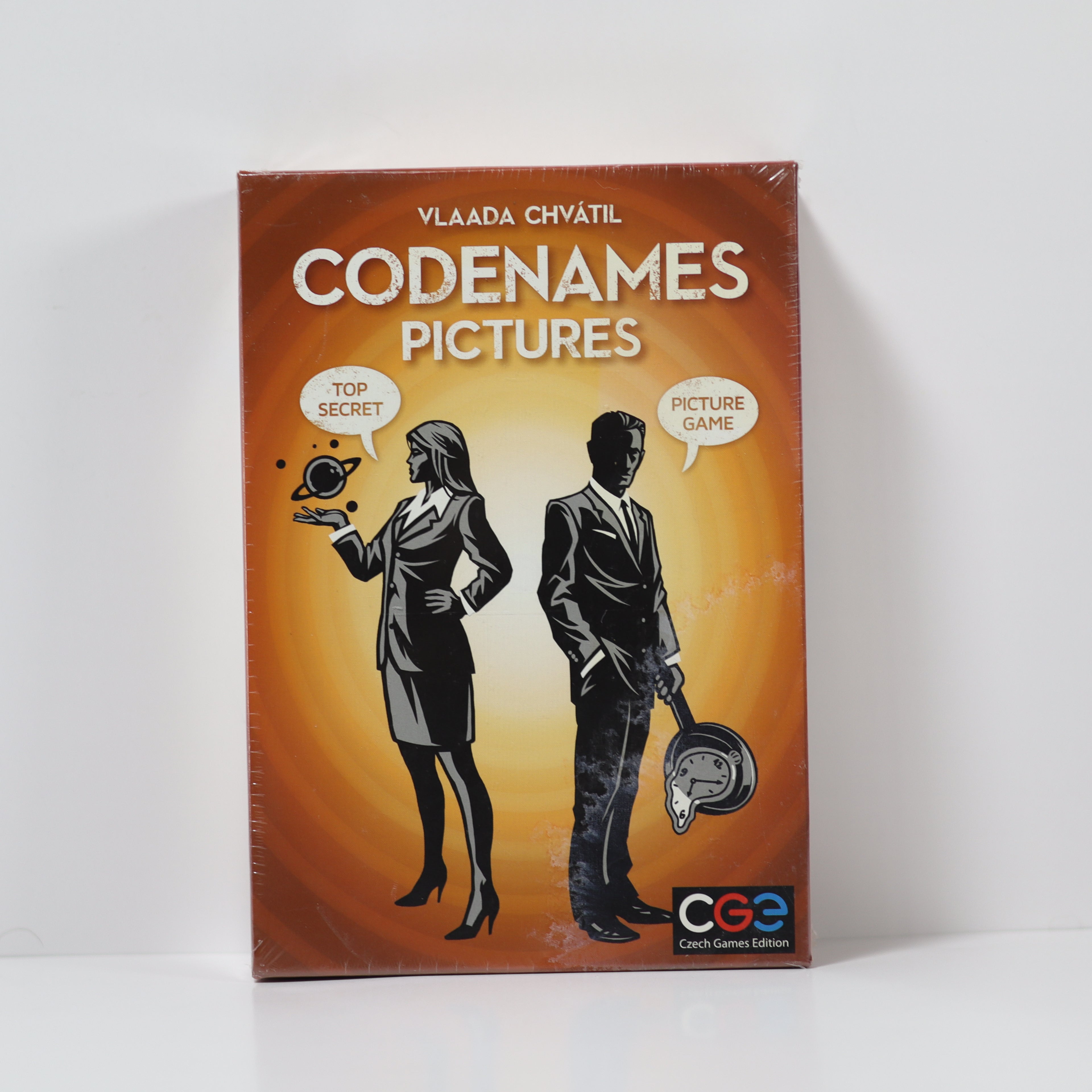 Board game box for 'Codenames Pictures' with silhouettes of a man and a woman on an orange background.