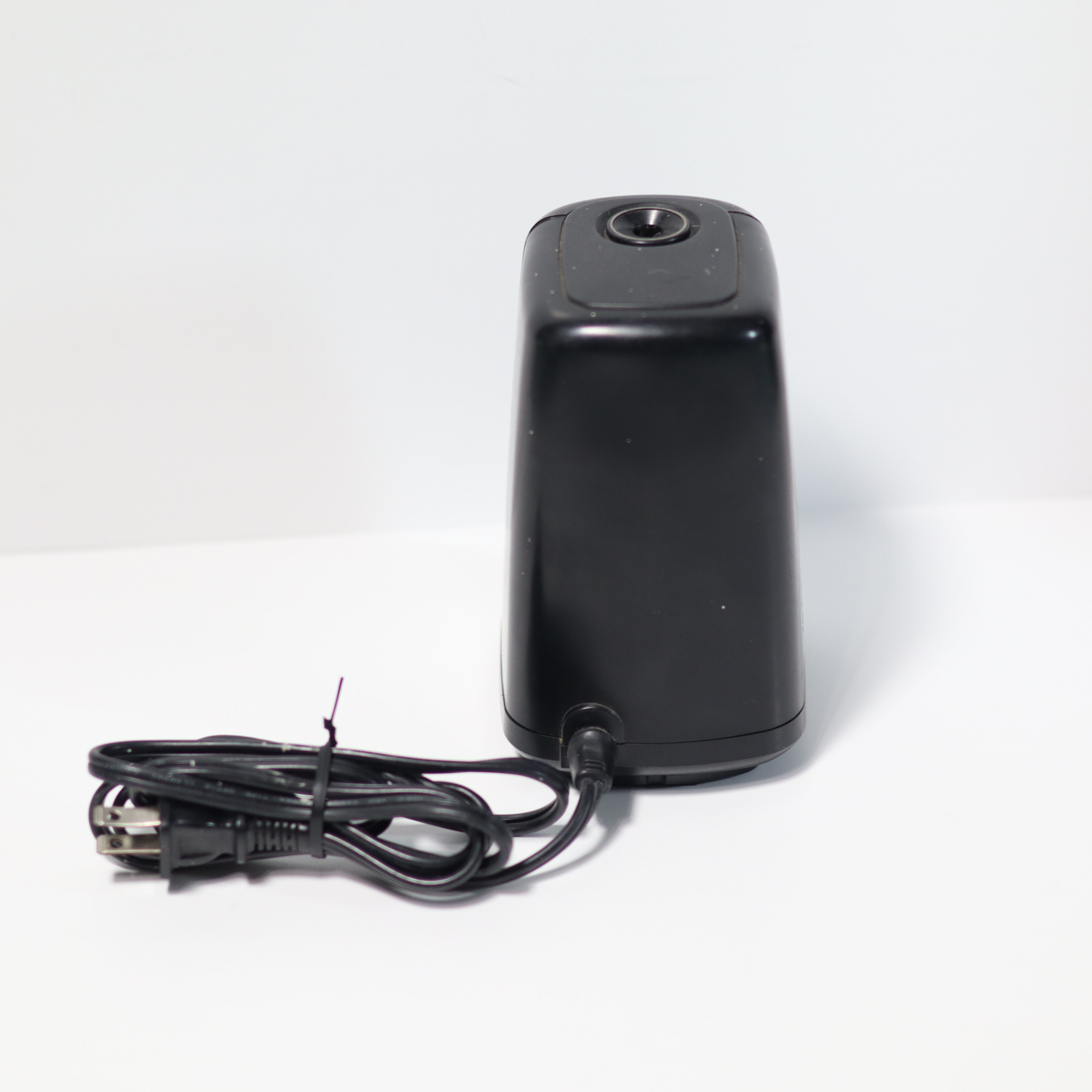 Black electric pencil sharpener with power cord on a white background