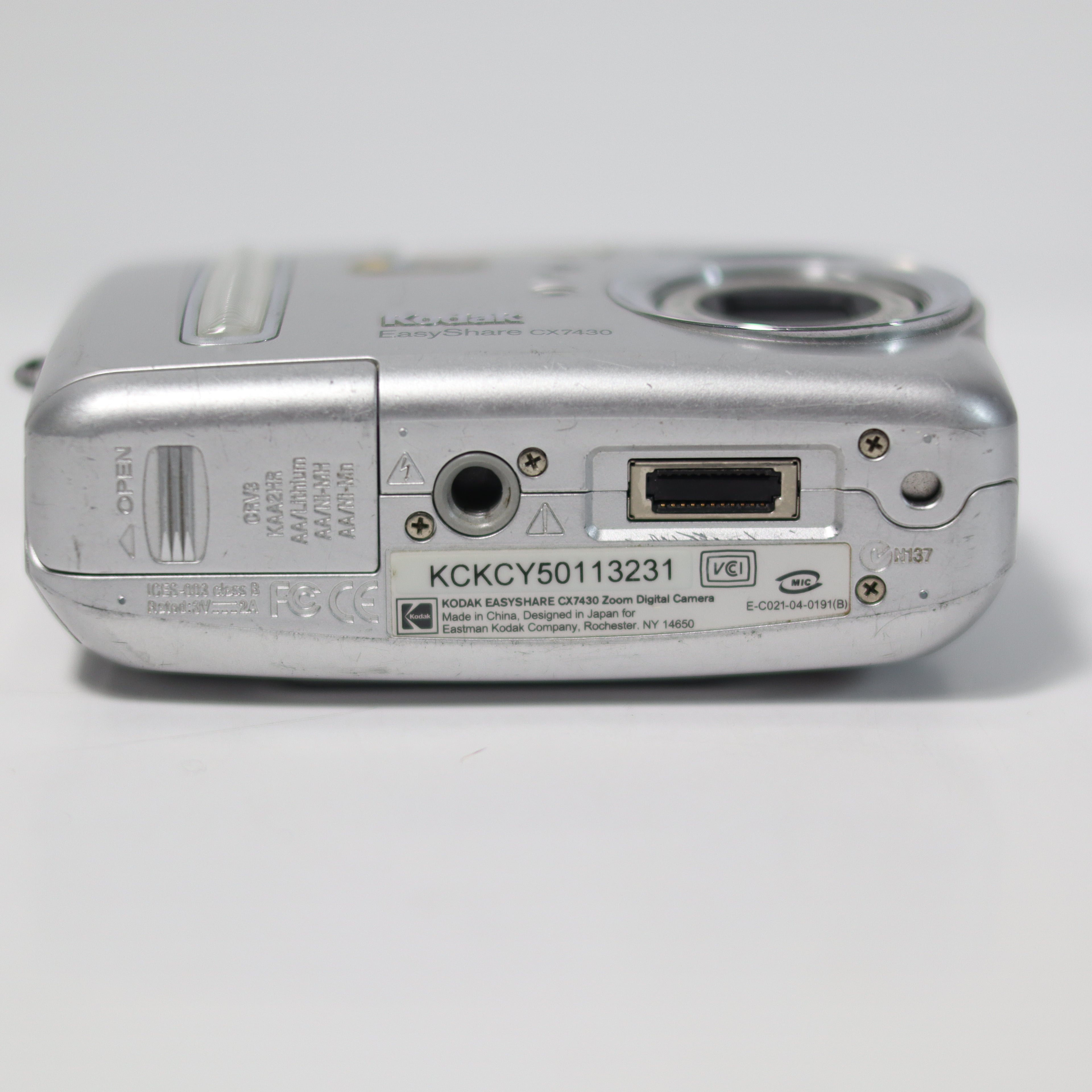 Back view of a silver digital camera on a white background