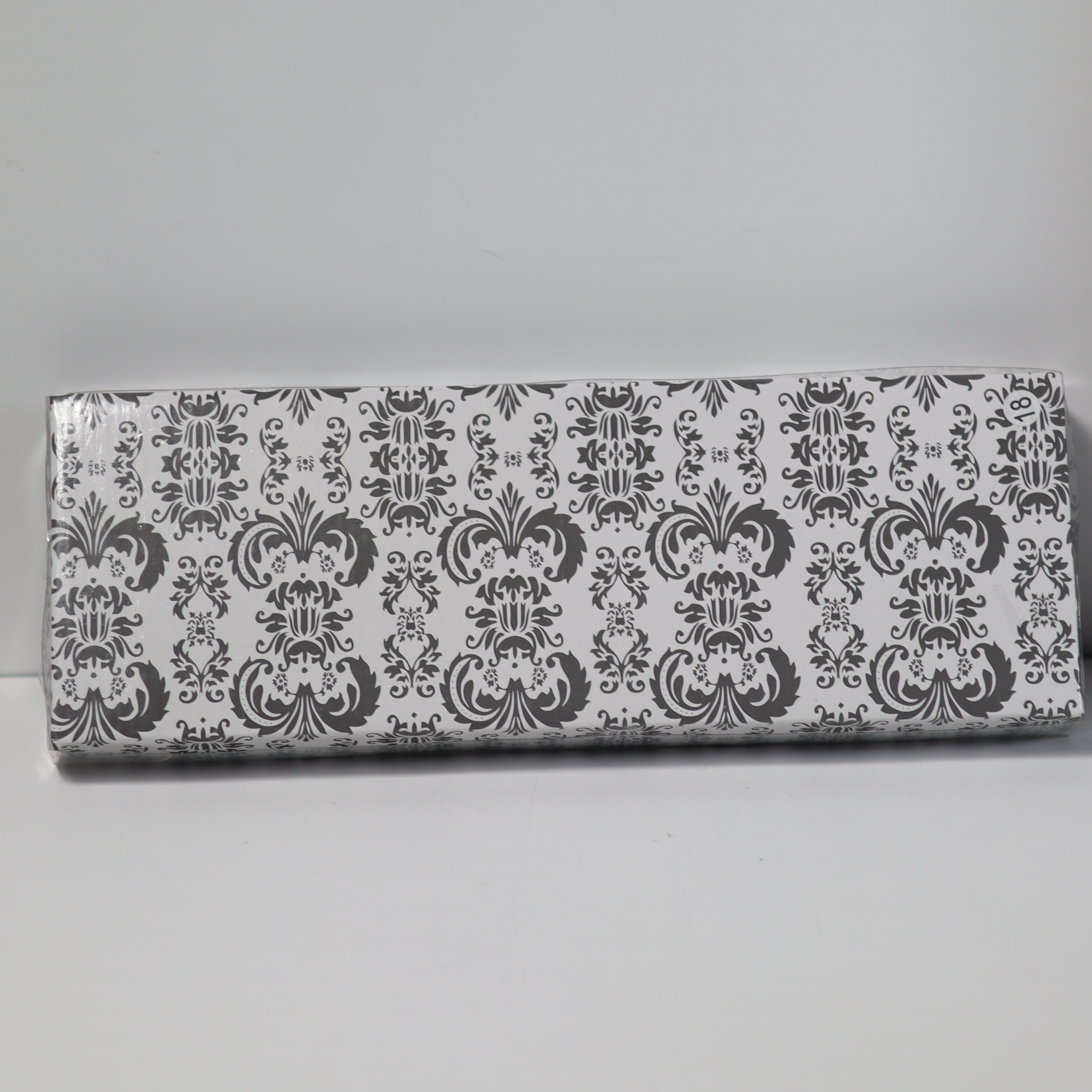 Rectangular box with decorative black and white pattern on a gray background