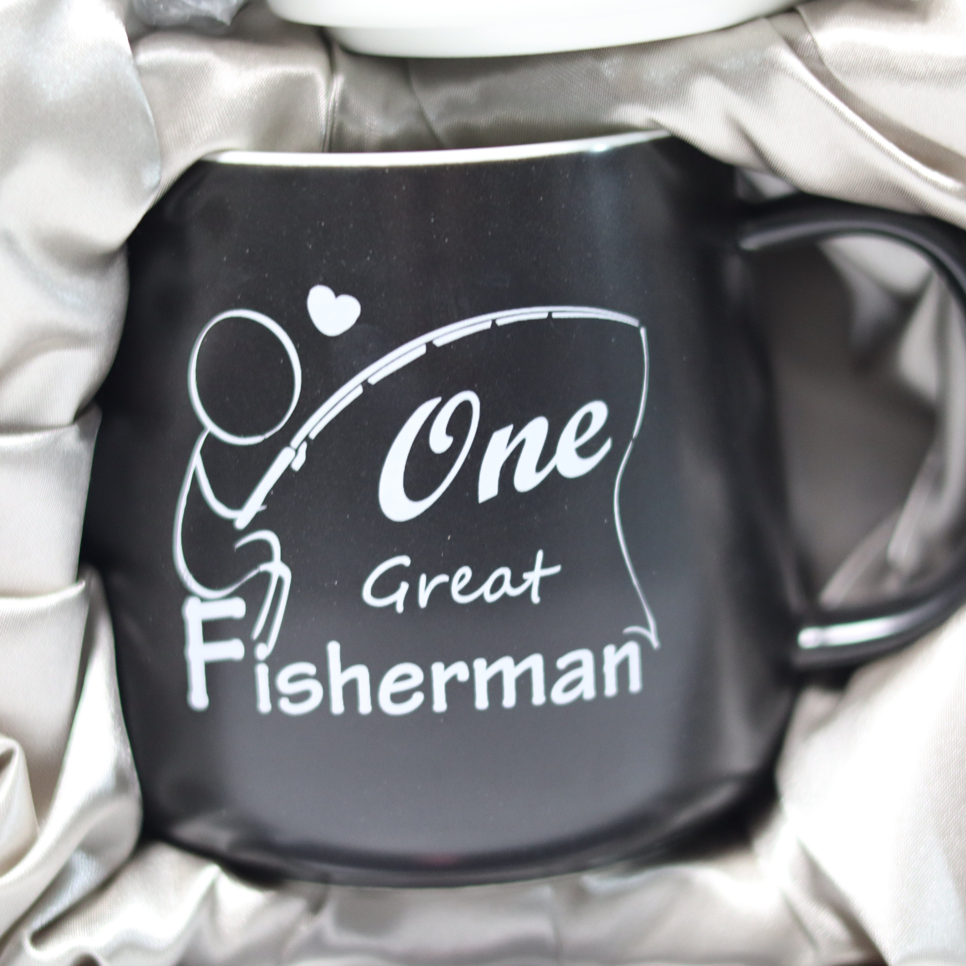 Black mug with 'One Great Fisherman' text and design on a white blanket