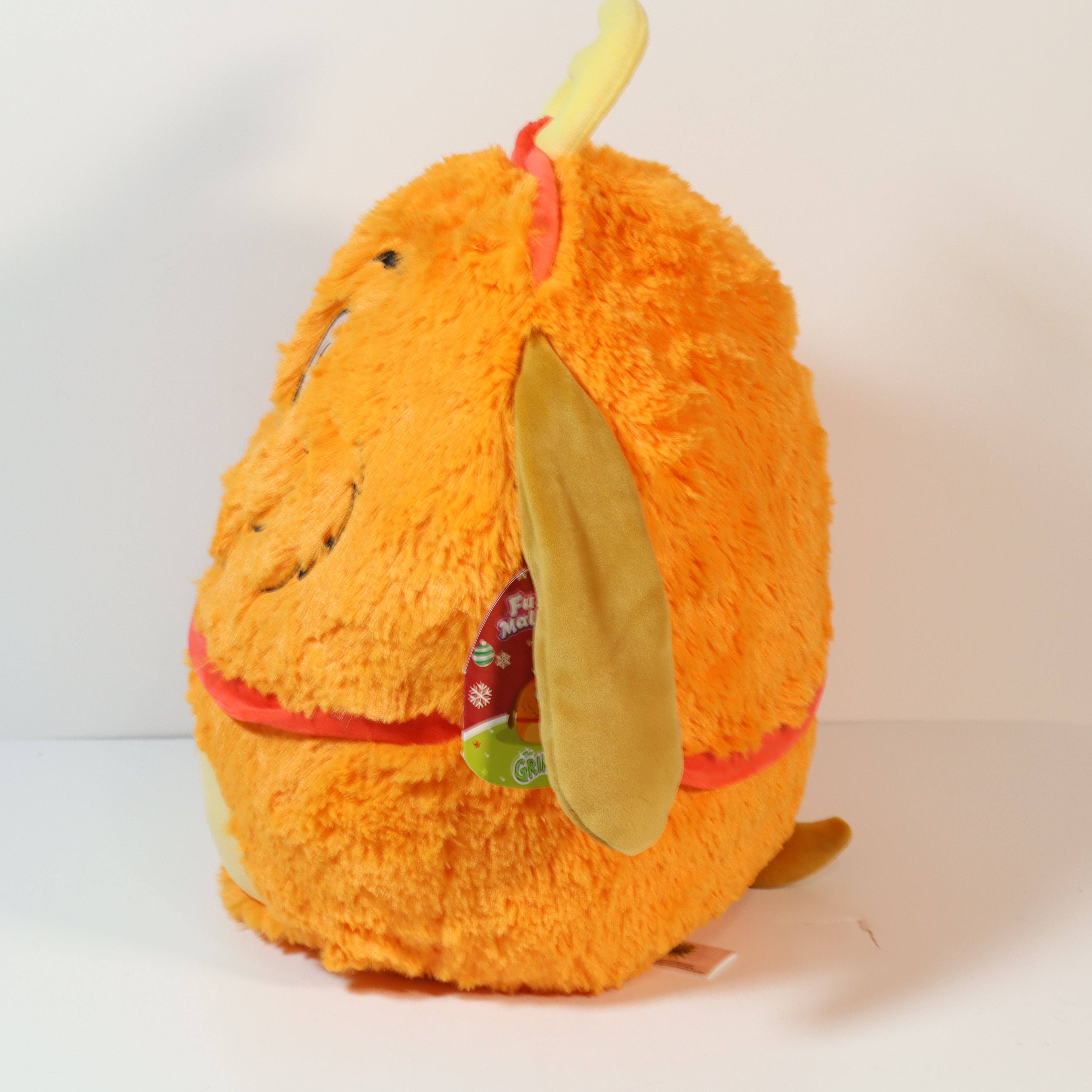 Orange plush toy with a tag on a white background