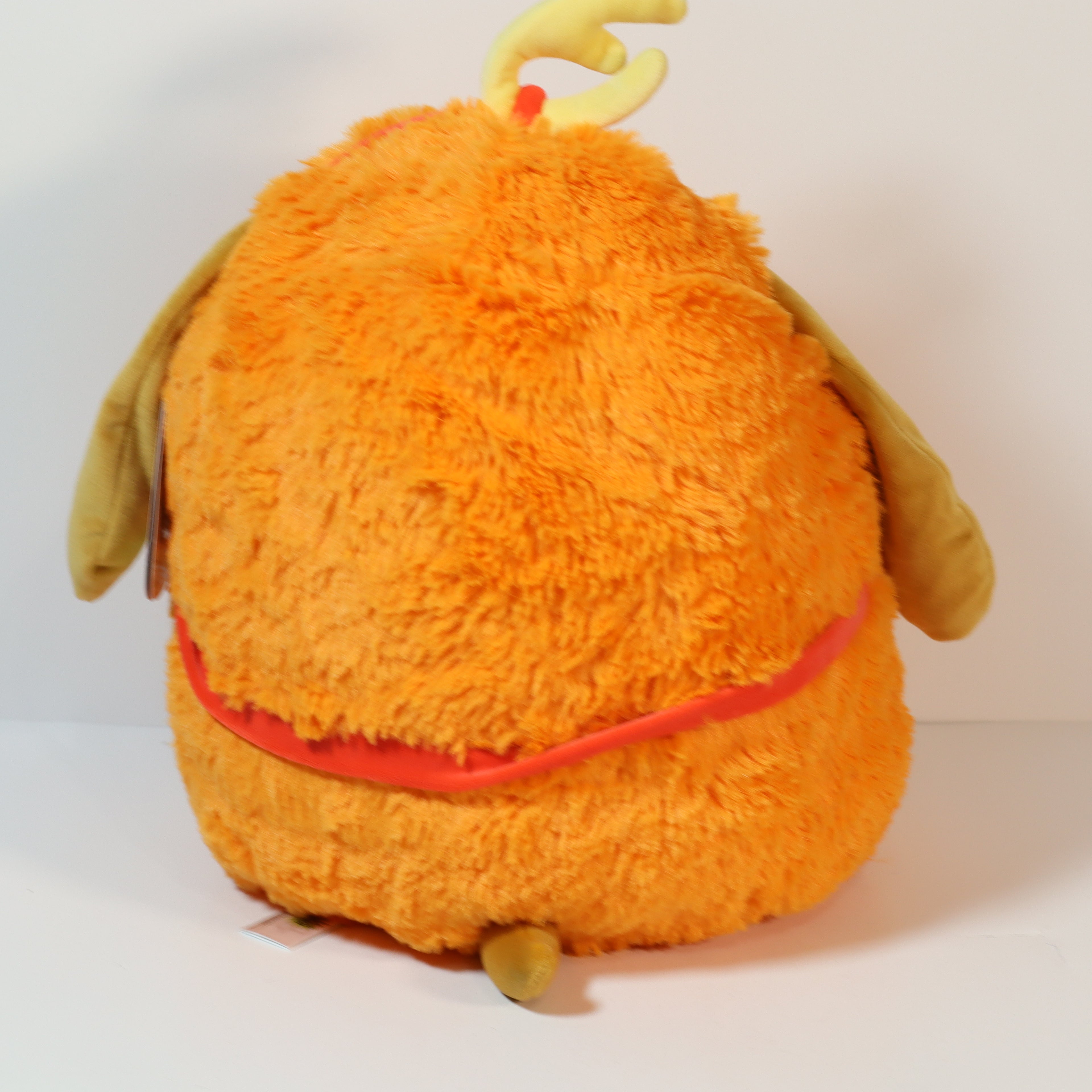 Orange plush toy with a red belt on a white background