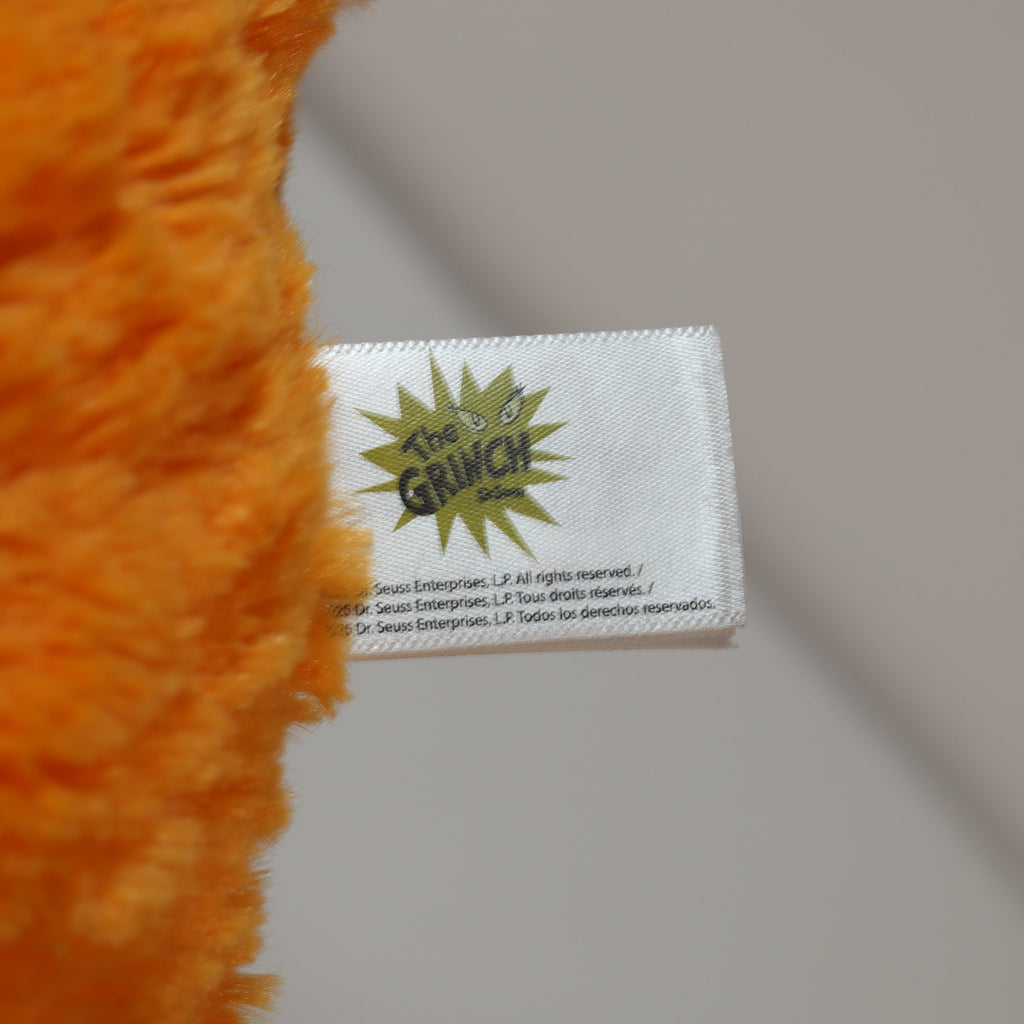 Close-up of a plush toy with a 'The Grinch' label on a neutral background